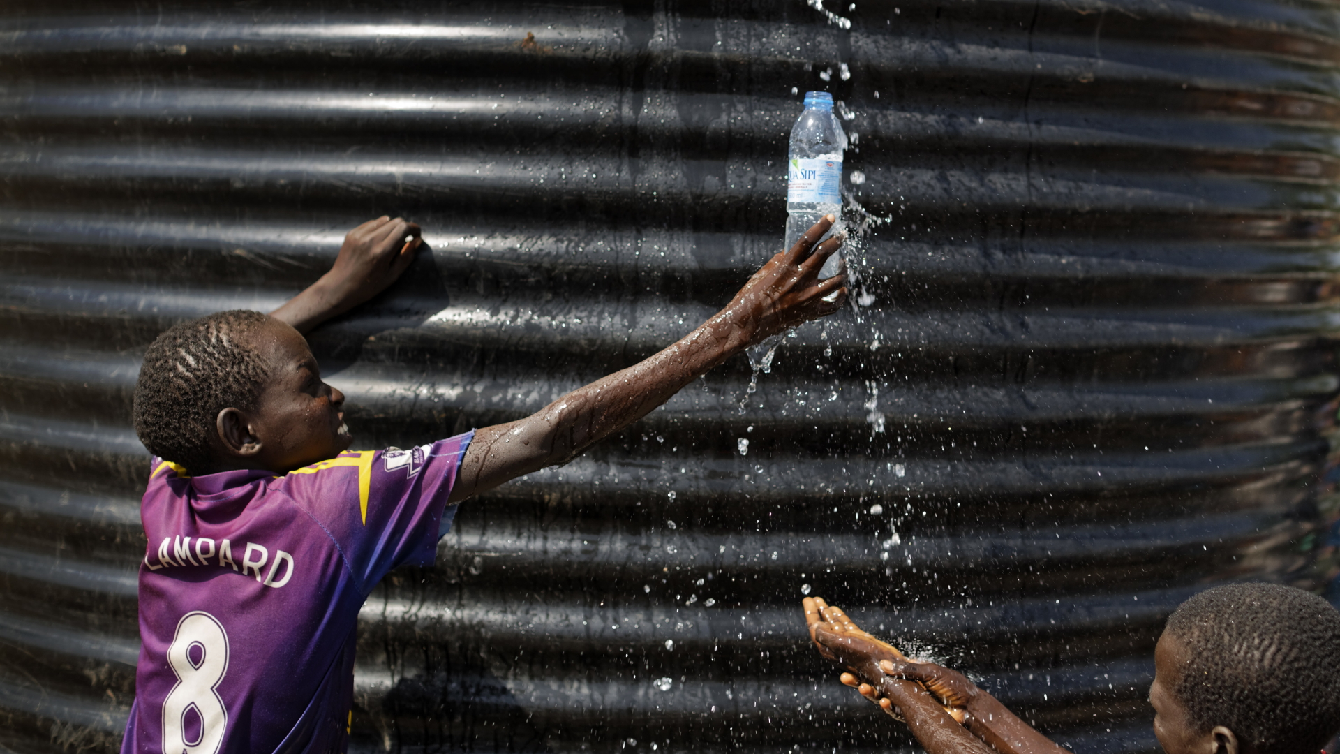 ganda, Imvepi: Ein Flüchtlingsjunge aus dem Südsudan fängt in einer Empfangsstelle für Flüchtlinge mit einer Flasche Wasser auf. (Archiv 2017) | dpa