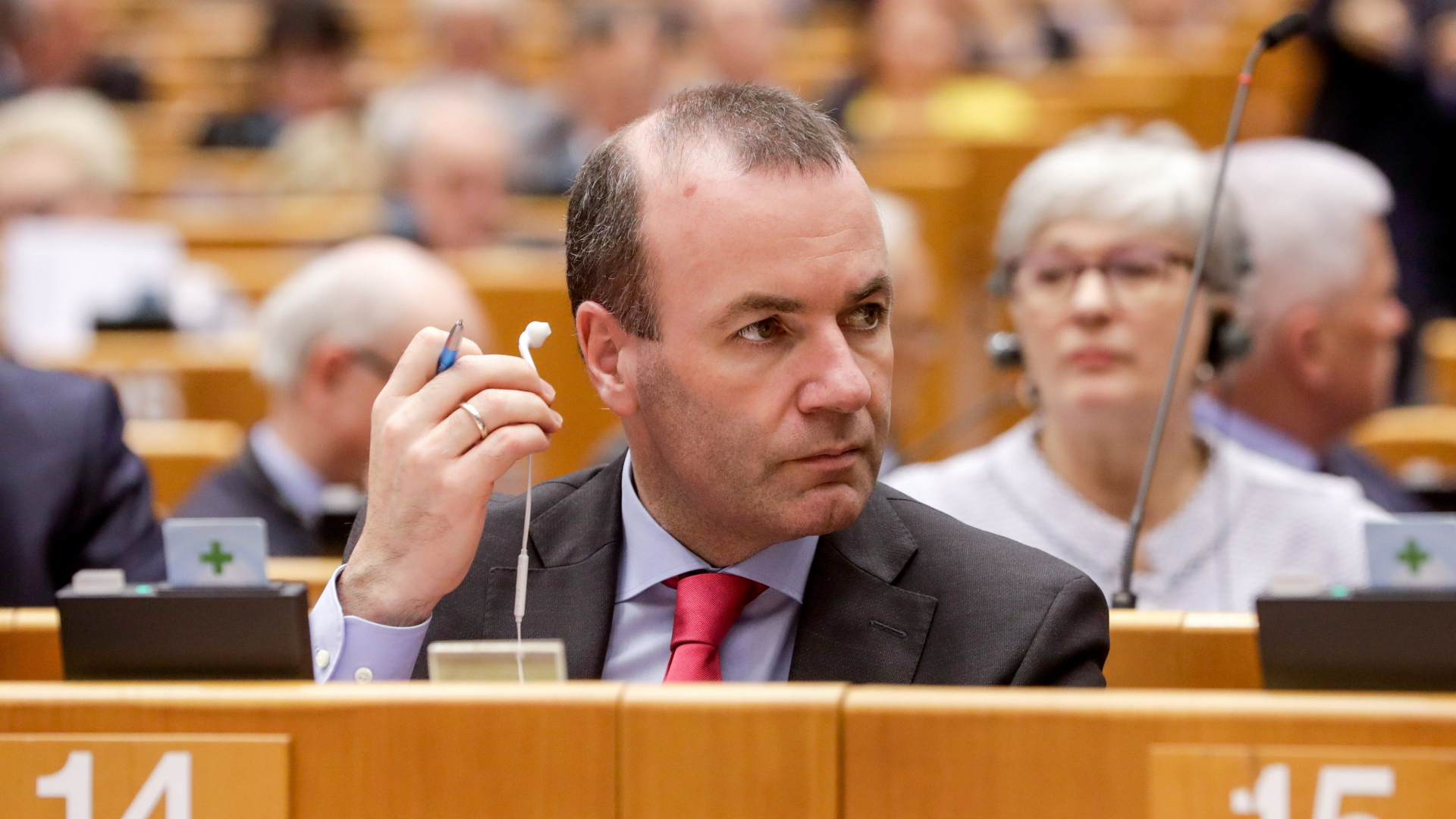 Der CSU-Europaabgeordnete Weber hält während einer Debatte einen Kopfhörer in der Hand