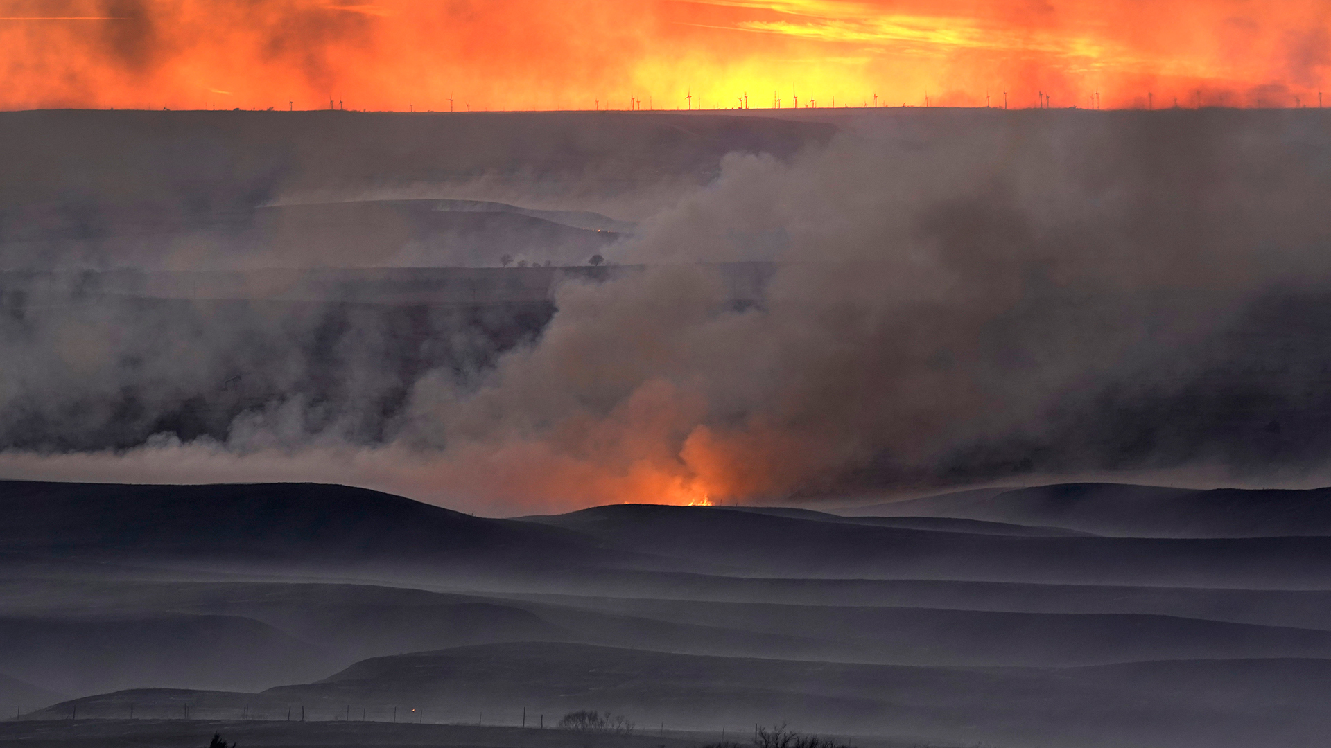 Ein Feuer brennt auf einer Weide. | picture alliance/dpa/AP