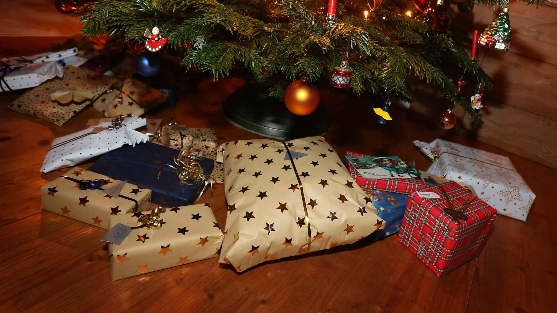 Unter einem Weihnachtsbaum liegen eingepackte Geschenke | dpa