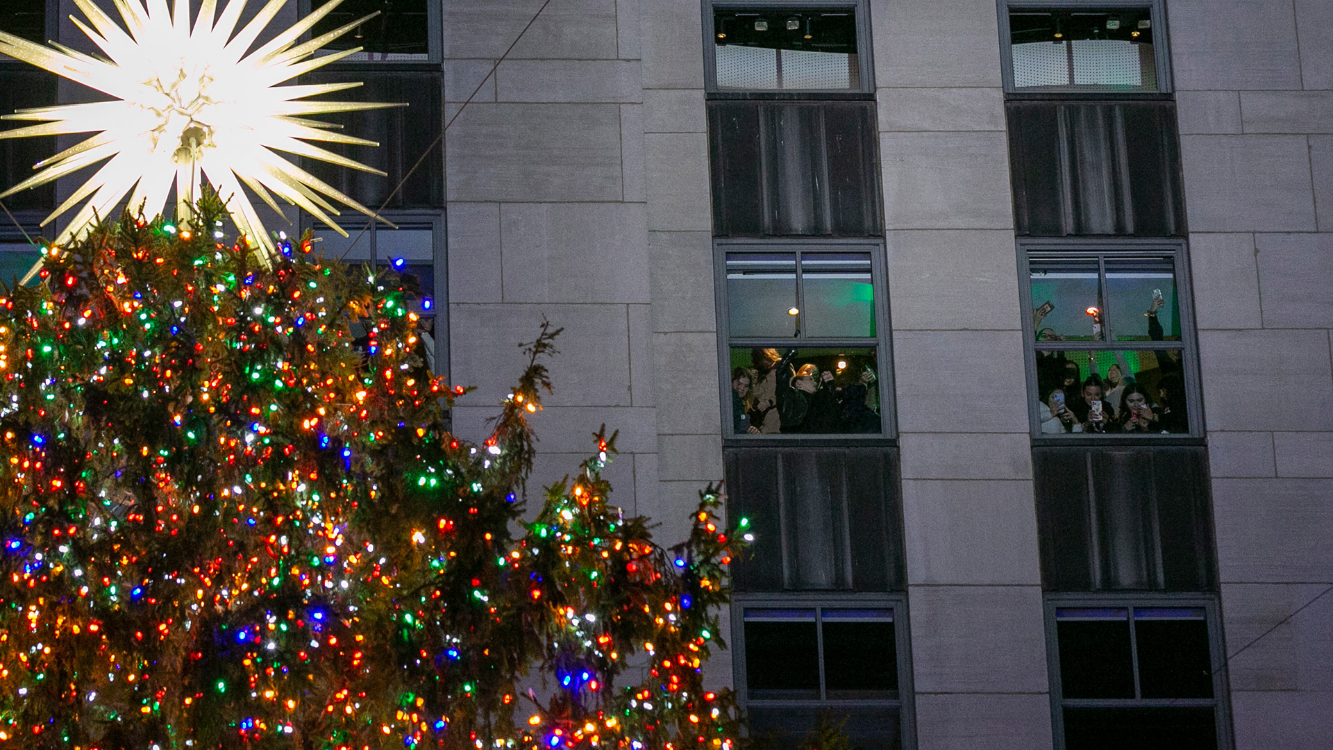 Menschen in einem der anliegenden Gebäude betrachten das Spektakel der Rockefeller Christmas Tree Lighting Ceremony 2022. | EPA