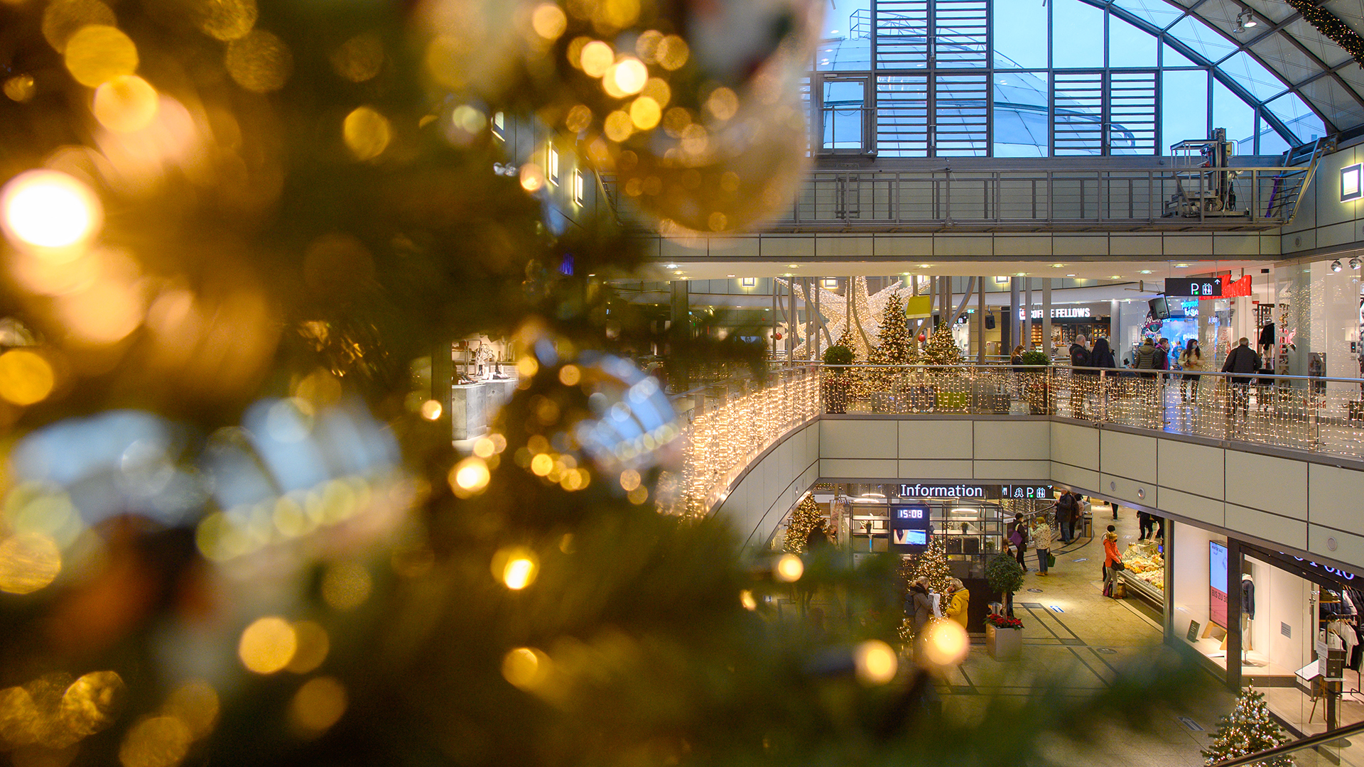 Kunden gehen durch ein weihnachtlich geschmücktes Einkaufszentrum in Magdeburg. | dpa