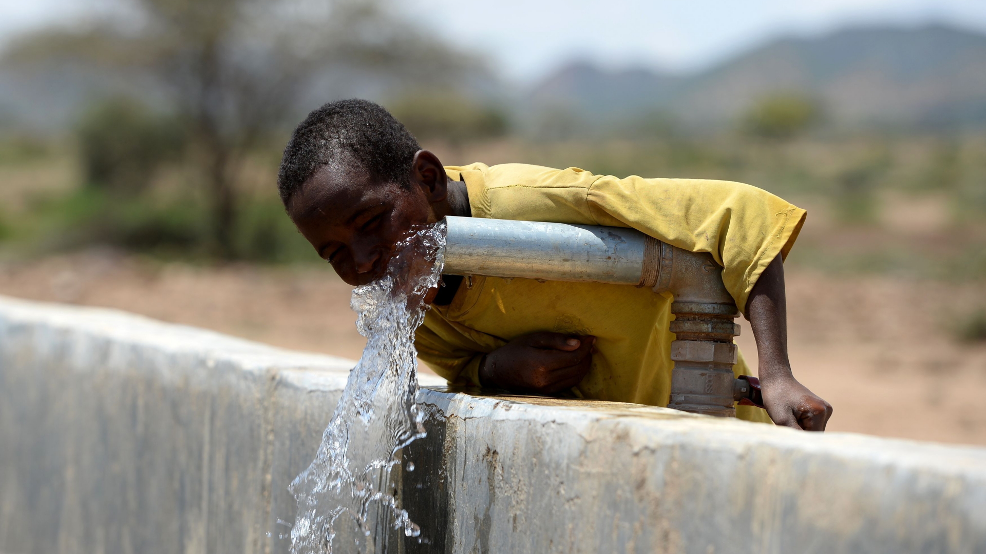 Ein Junge trinkt in Afraaga (Somalia) Wasser aus einem Wasserrohr, dass von der Hilfsorganisation CARE International eingerichtet wurde, um den Zugang zu sauberem Trinkwasser sicherzustellen. | dpa
