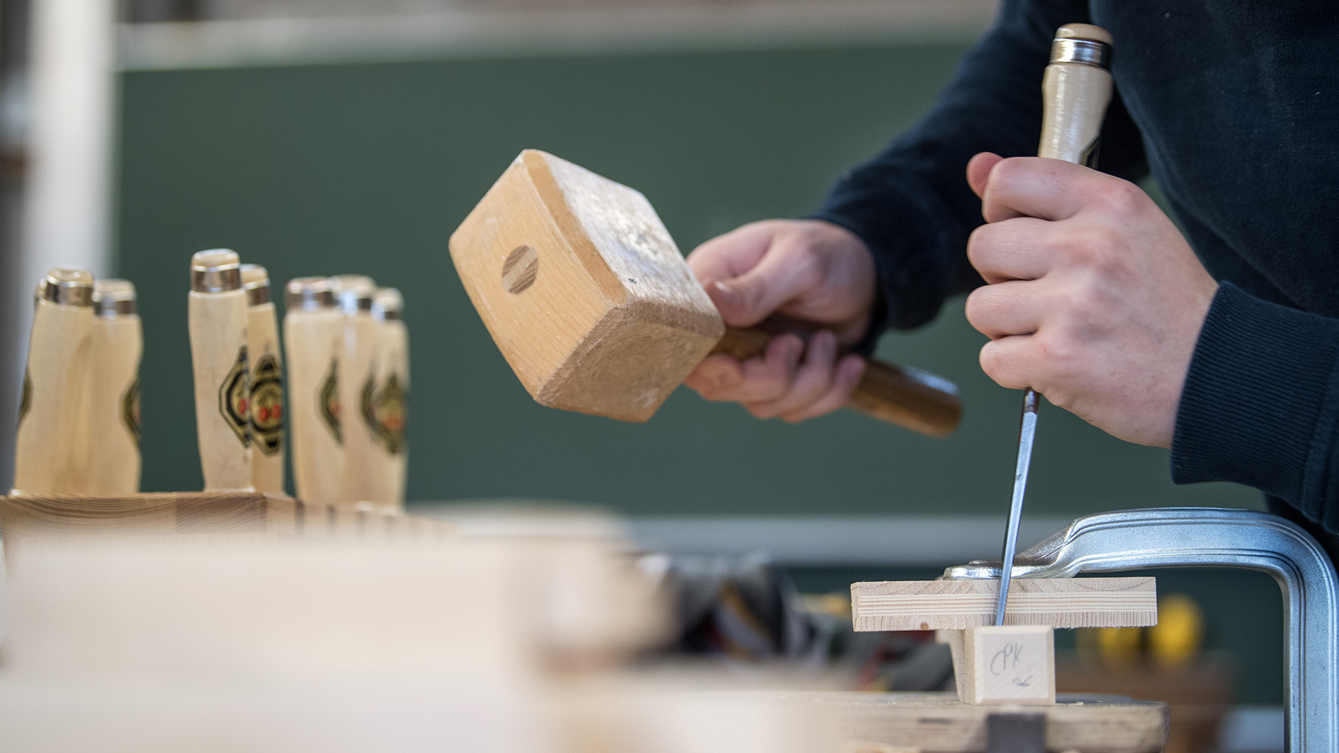 Ein Auszubildender arbeitet an einer Berufsschule in Ludwigsburg (Baden-Württemberg) an einer Werkbank mit Holz.