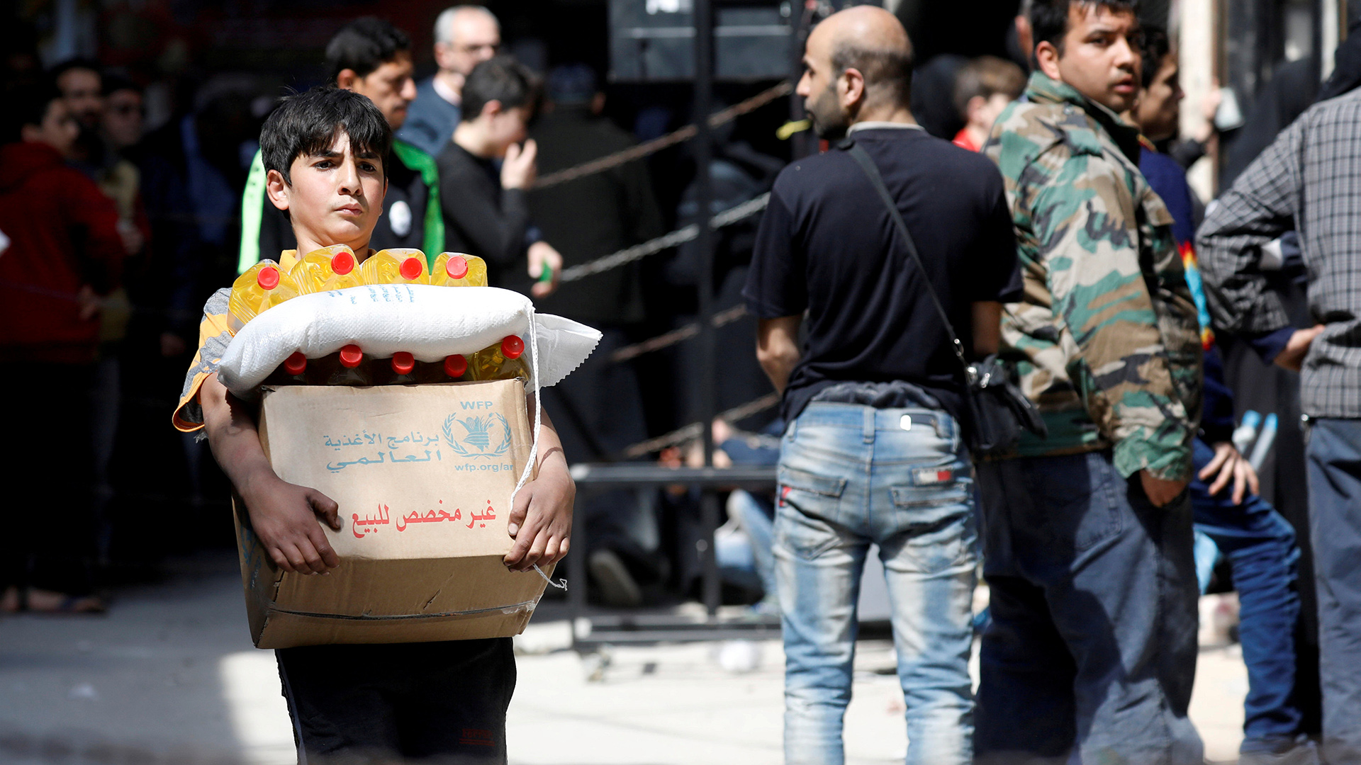 Ein Junge trägt einen Karton mit Nahrungsmittelhilfe des Welternährungsprogramms der UNO, Syrien/Archivbild. | REUTERS