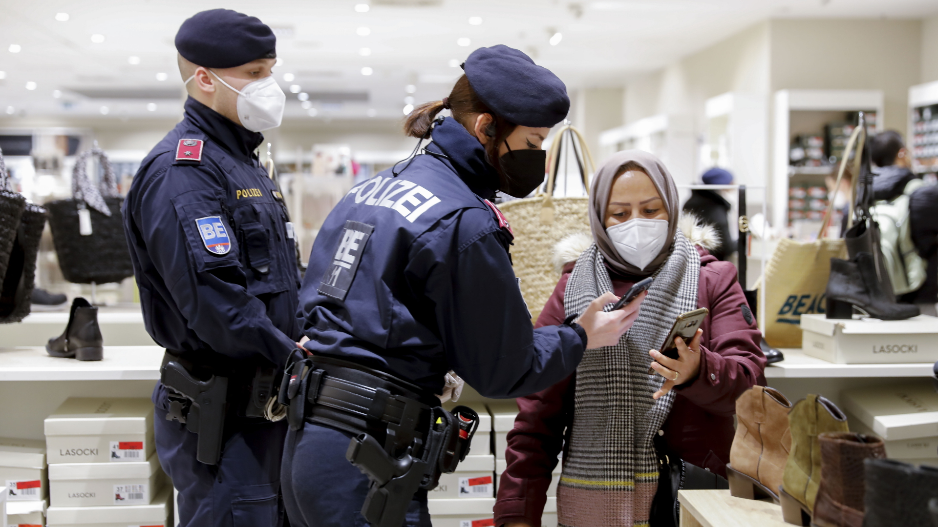 Eine Polizistin in Wien kontrolliert den Impfstatus auf dem Handy einer Frau. | dpa