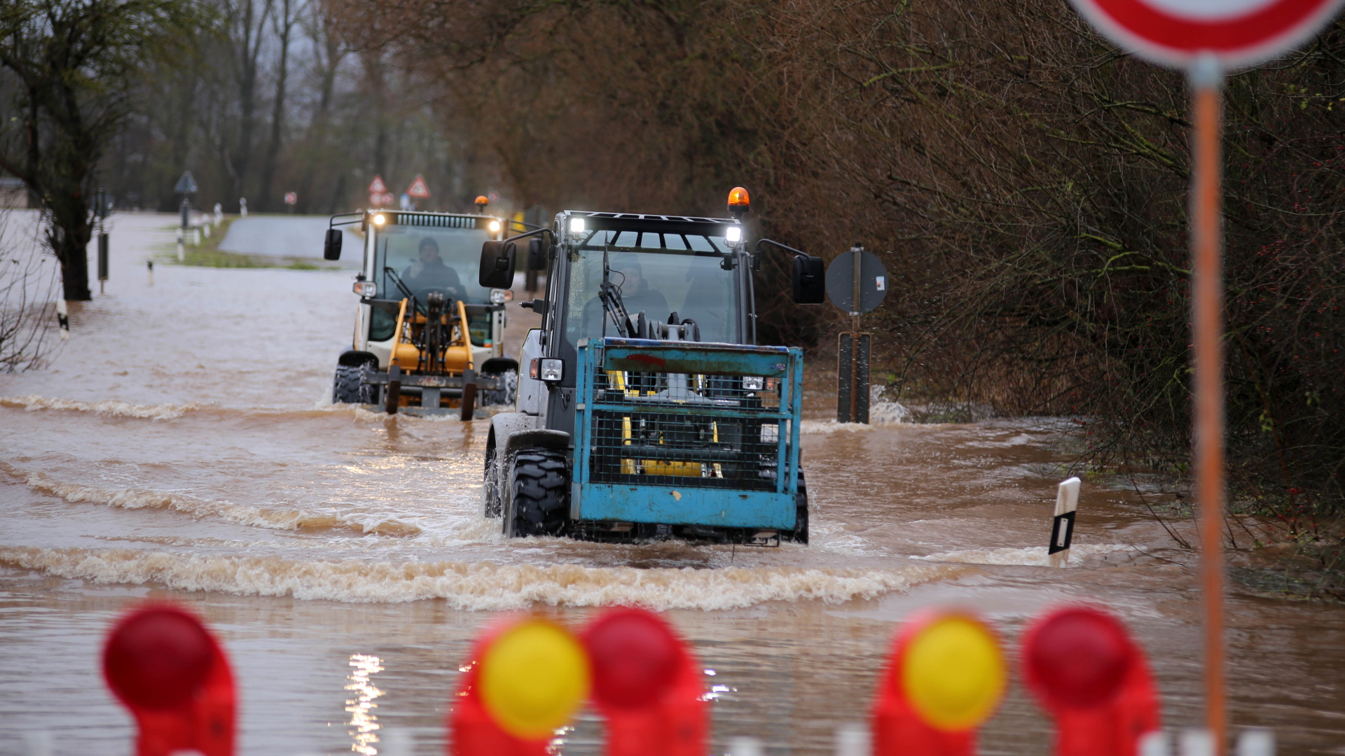  Zwei Traktoren verlassen den Ort Windehausen über eine von Hochwasser überflutete Straße.
