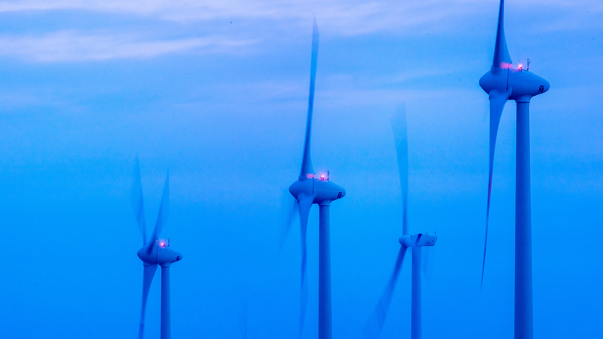 Windkraftanlagen drehen sich vor Sonnenaufgang in einem Windpark. | dpa