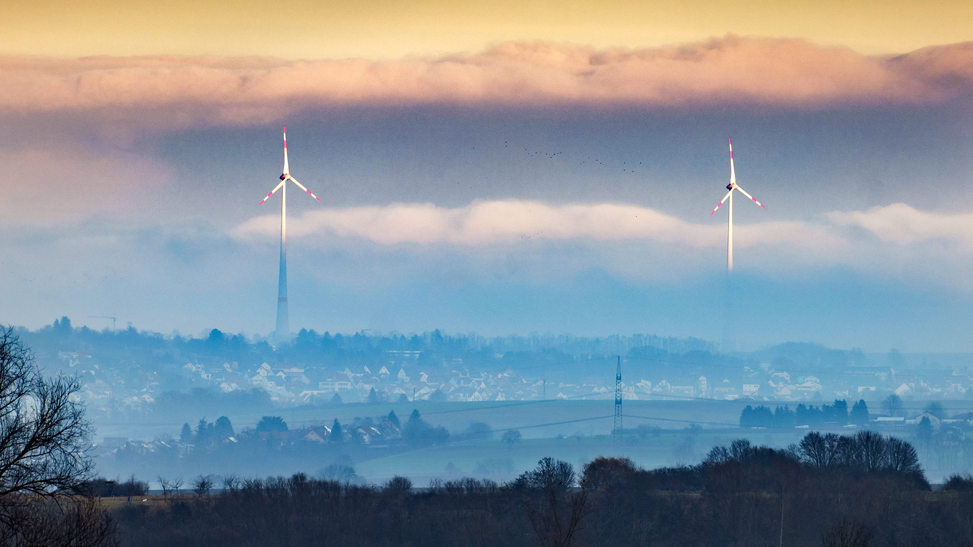Zwei Windräder schauen aus dem Dunst über der Wetterau heraus beim abendlichen Blick in die ferne vom nordöstlichen Frankfurter Stadtteil Bergen. | dpa