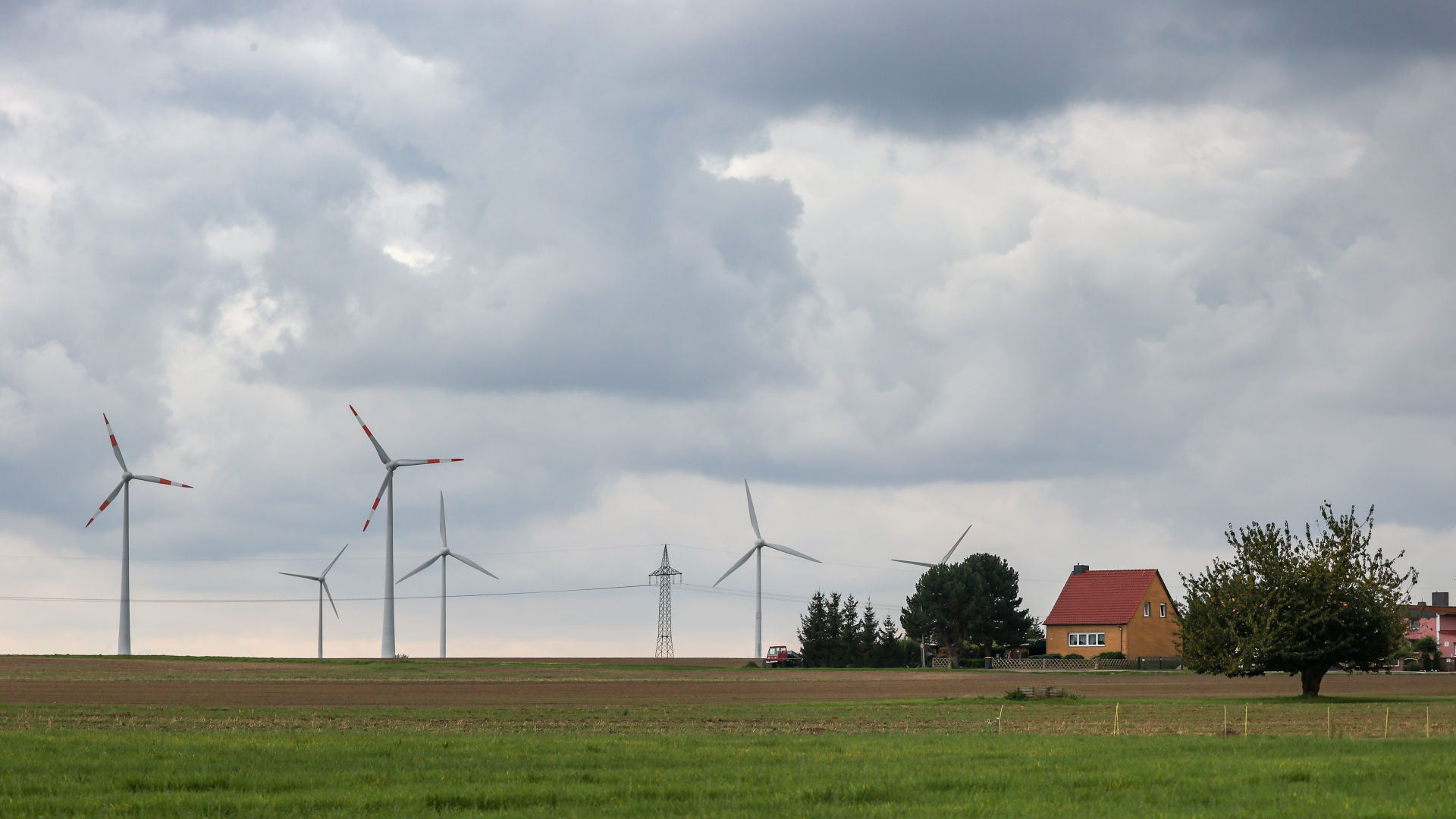 Windräder drehen sich hinter einem Dorf in Sachsen-Anhalt (Archivbild September 2021). | dpa