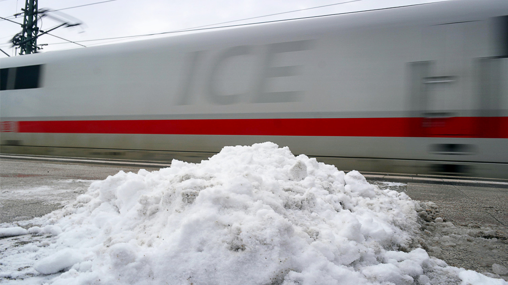 Schnee liegt auf dem Bahnsteig des Bahnhofs Gesundbrunnen in Berlin, während ein ICE die Fahrt aufnimmt. 