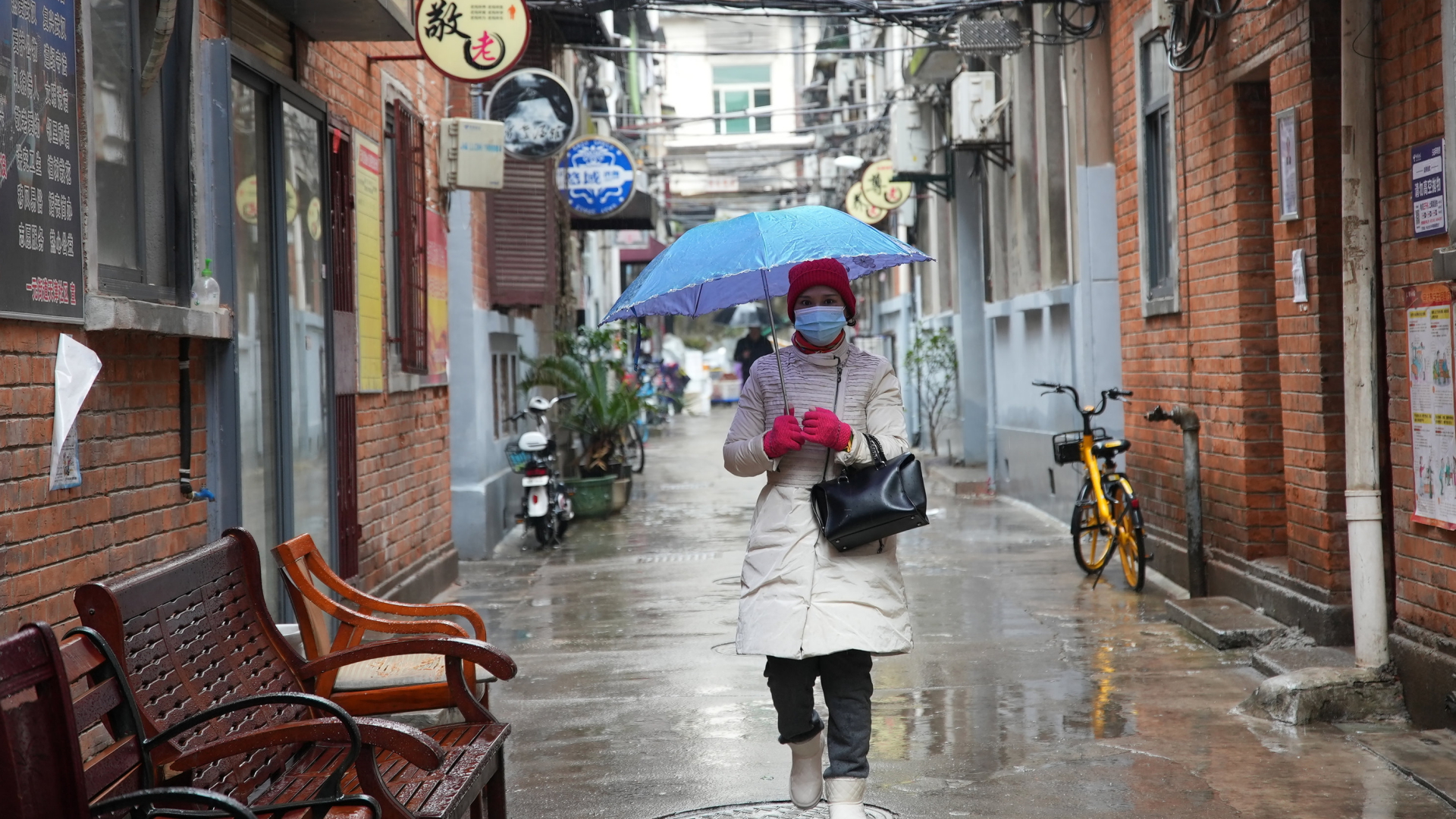 Eine Frau mit Regenschirm und Maske in Wuhan. | AP