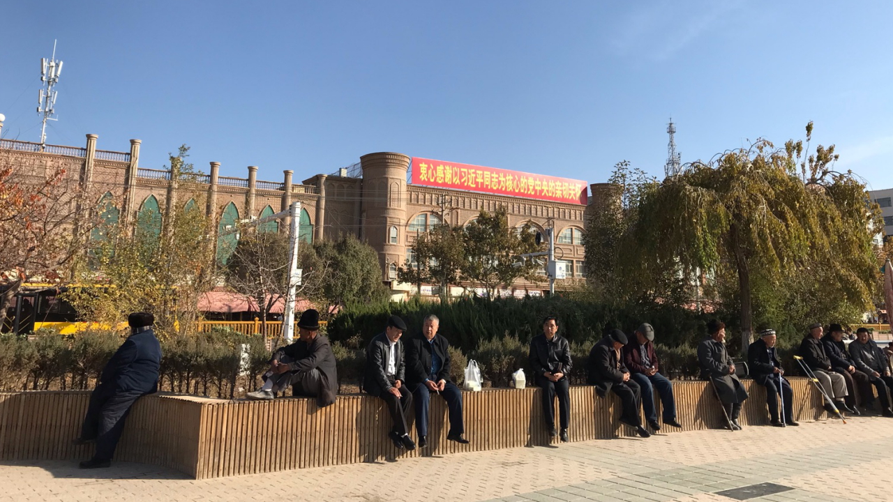 Männer sitzen in Kaschgar in der nordwestchinesischen Region Xinjiang auf einer Mauer | dpa