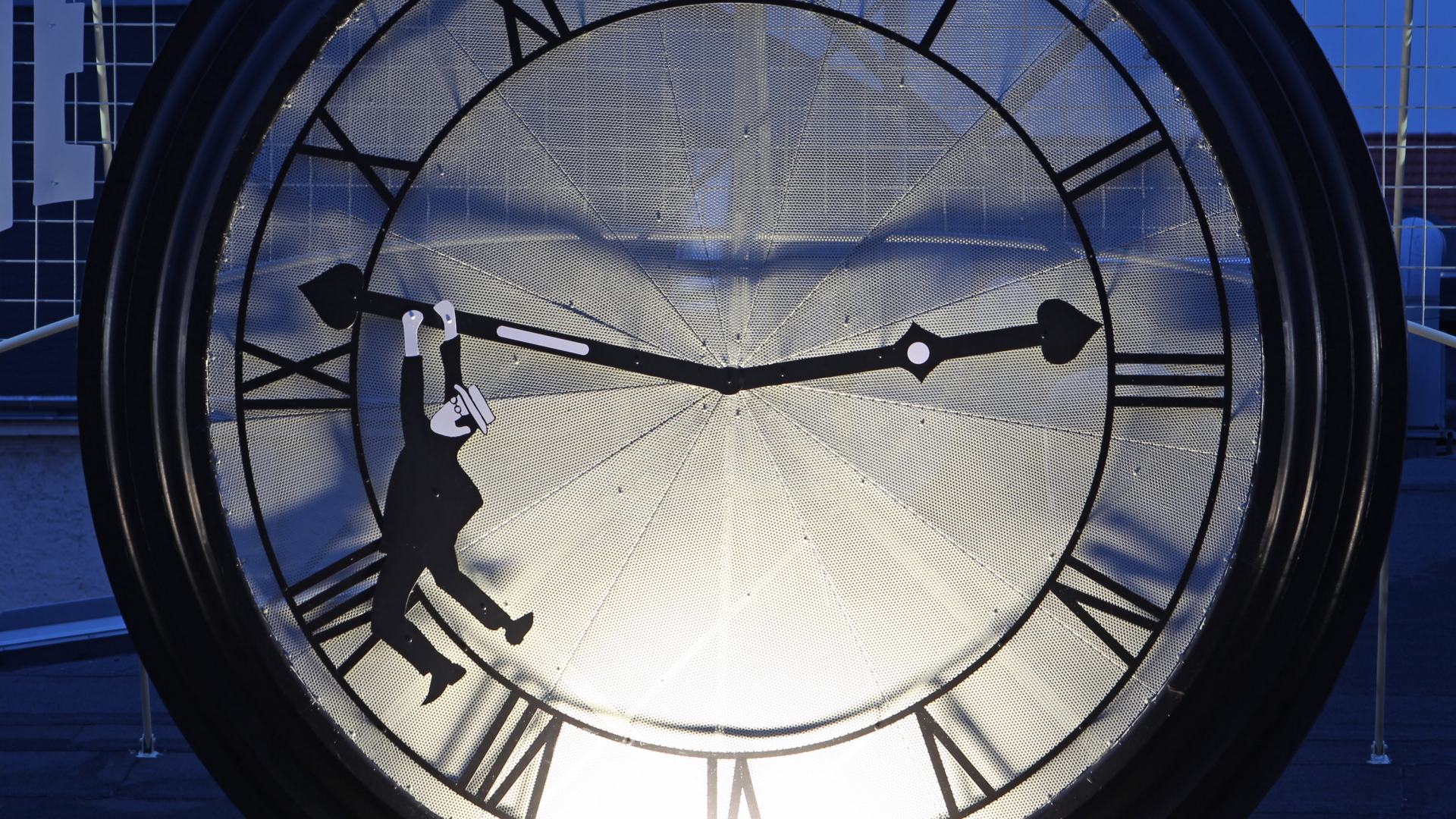 Ein Motiv aus der Stummfilm-Komödie "Safety Last!": Ein Männchen in schwarzem Anzug hängt an einer überdimensionalen Uhr. | dpa