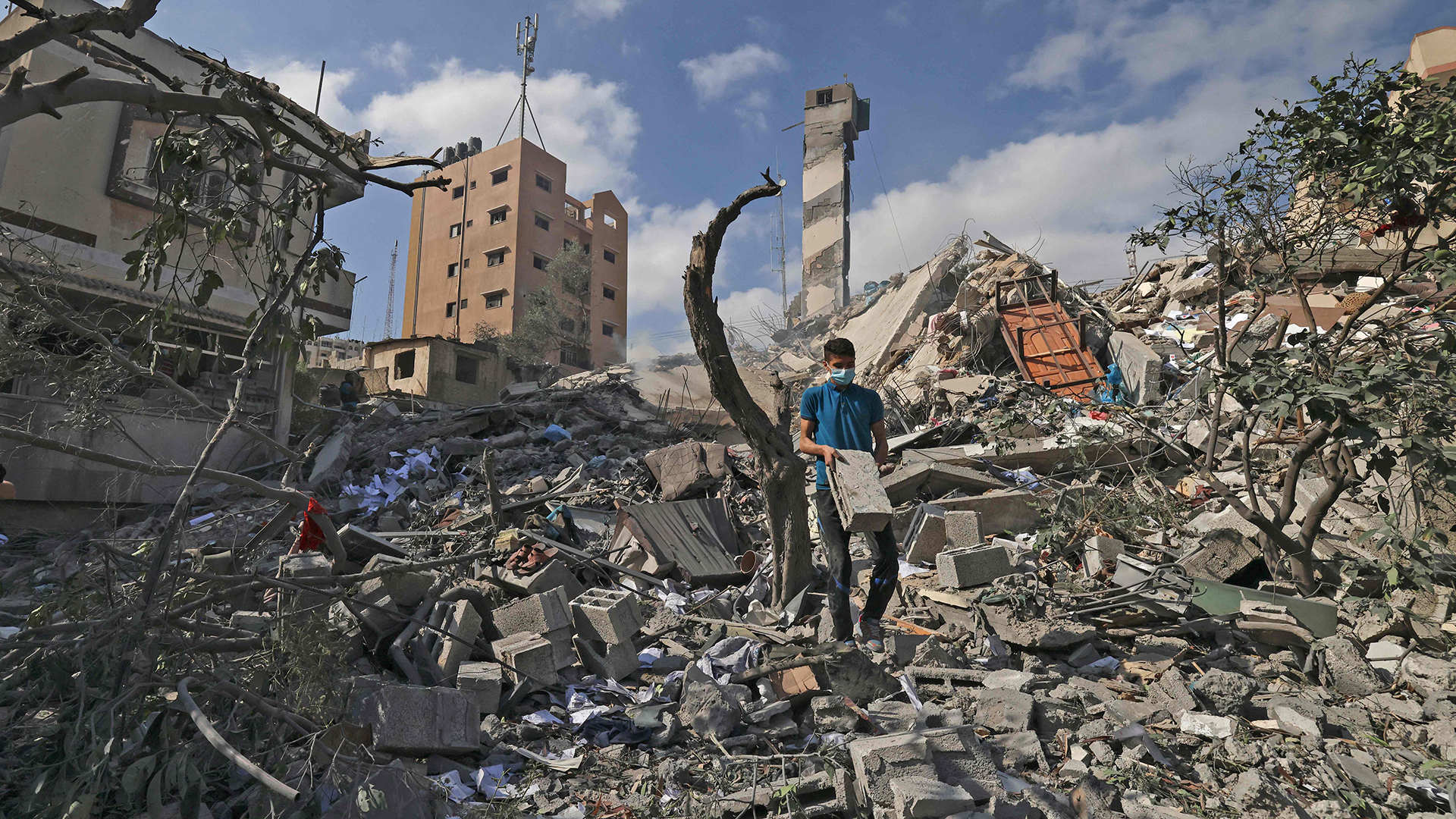 Ein Mann geht in Gaza-Stadt über die Trümmer eines Hauses. | AFP
