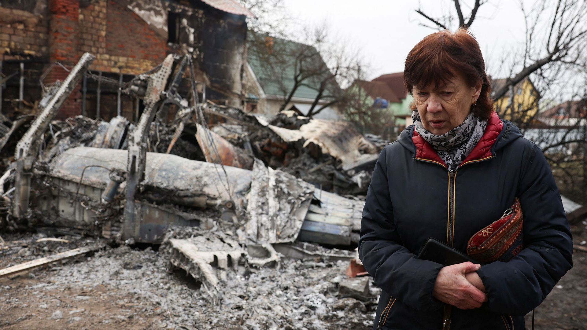 Eine Frau geht um das Wrack eines nicht identifizierten Flugzeugs herum, das in einem Wohngebiet in Kiew in ein Haus stürzte. | Bildquelle: REUTERS