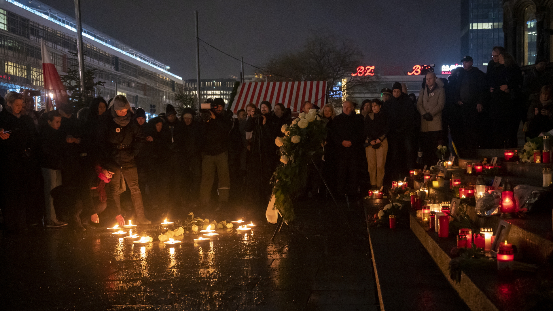 Menschen stehen bei der Gedenkveranstaltung zum Terroranschlag auf dem Breitscheidplatz hinter brennenden Kerzen. | dpa