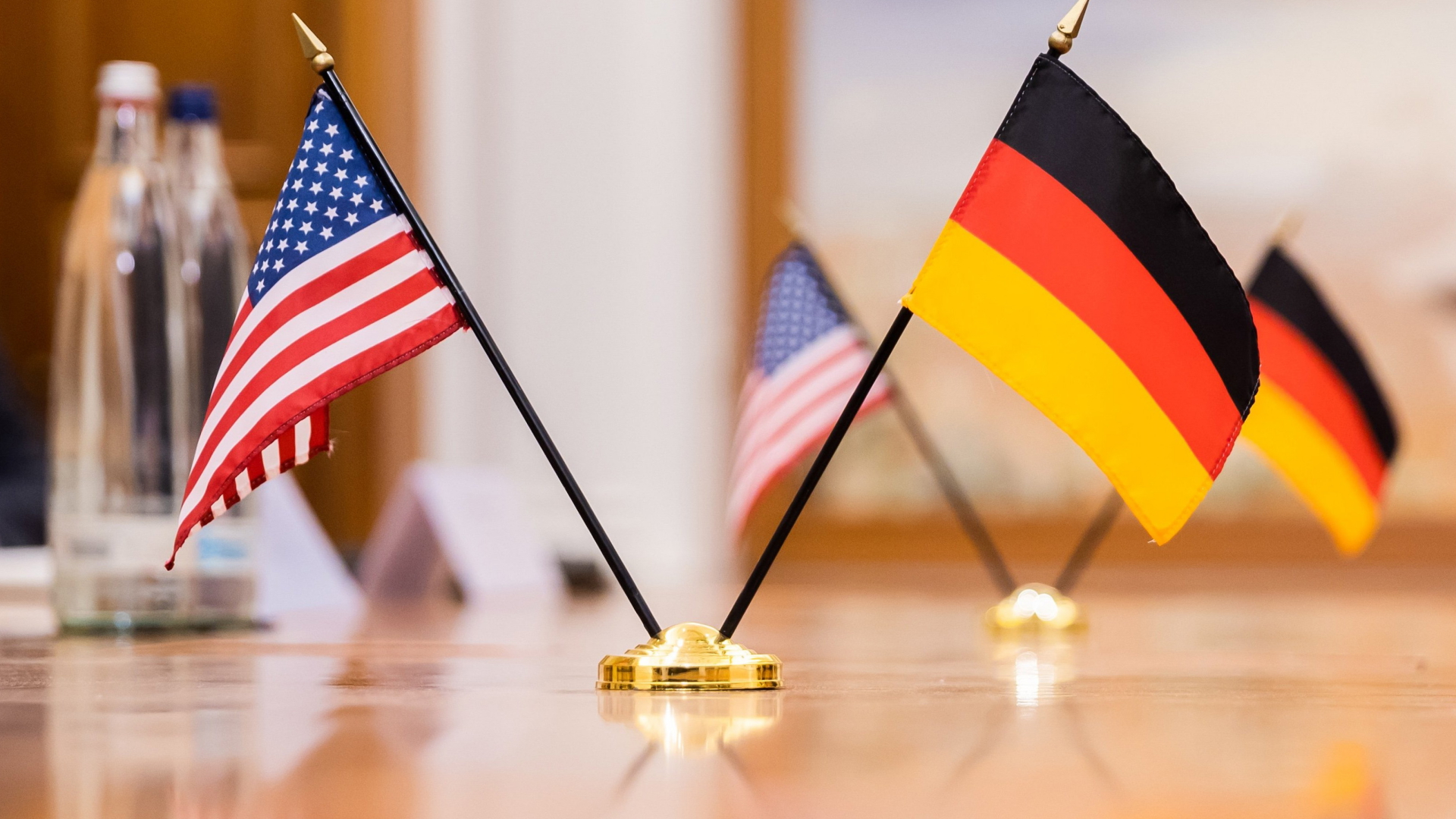Die Flaggen der USA und Deutschland stehen auf einem Tisch.