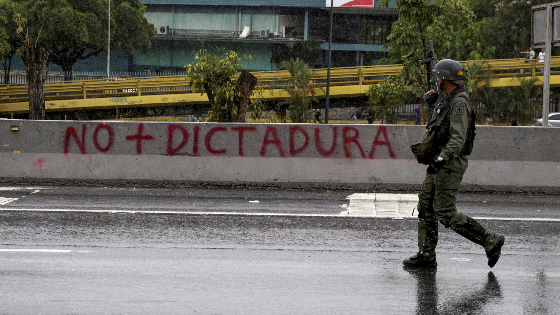 Ein Polizist läuft vor einem "Kein-Diktatur-Graffity" entlang