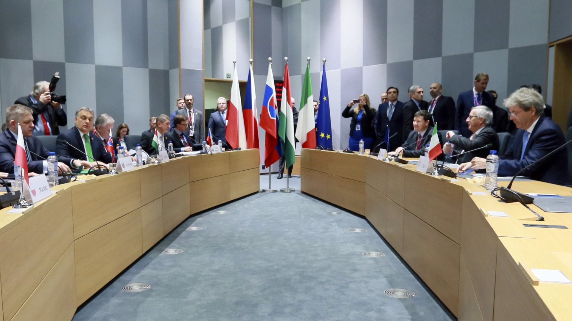 Regierungschefs der Visegrad-Staaten am Tisch, in der Mitte Flaggen
