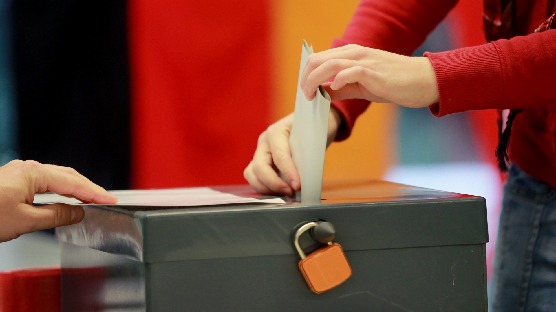 Ein Wähler steckt seinen Stimmzettel in eine Wahlurne.
