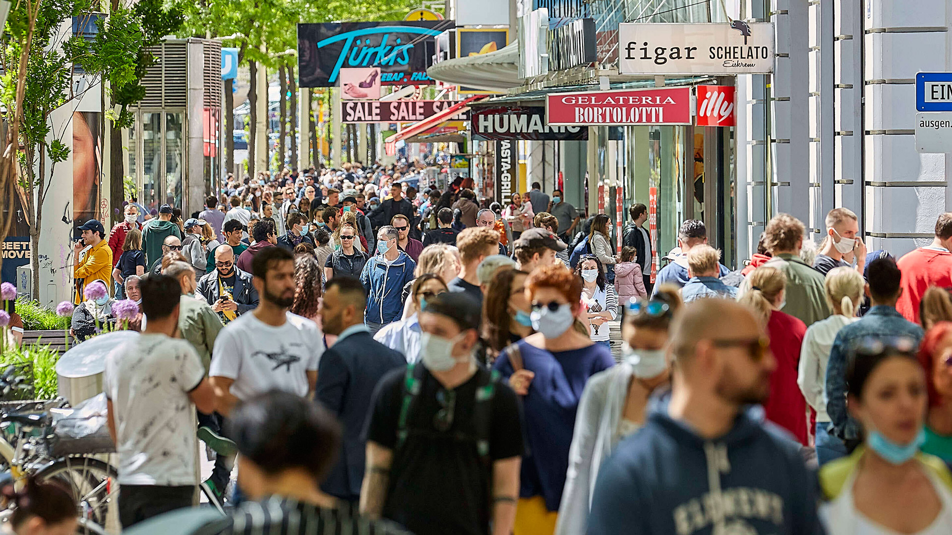 Menschen mit und ohne Atemschutzmasken in Fußgängerzone