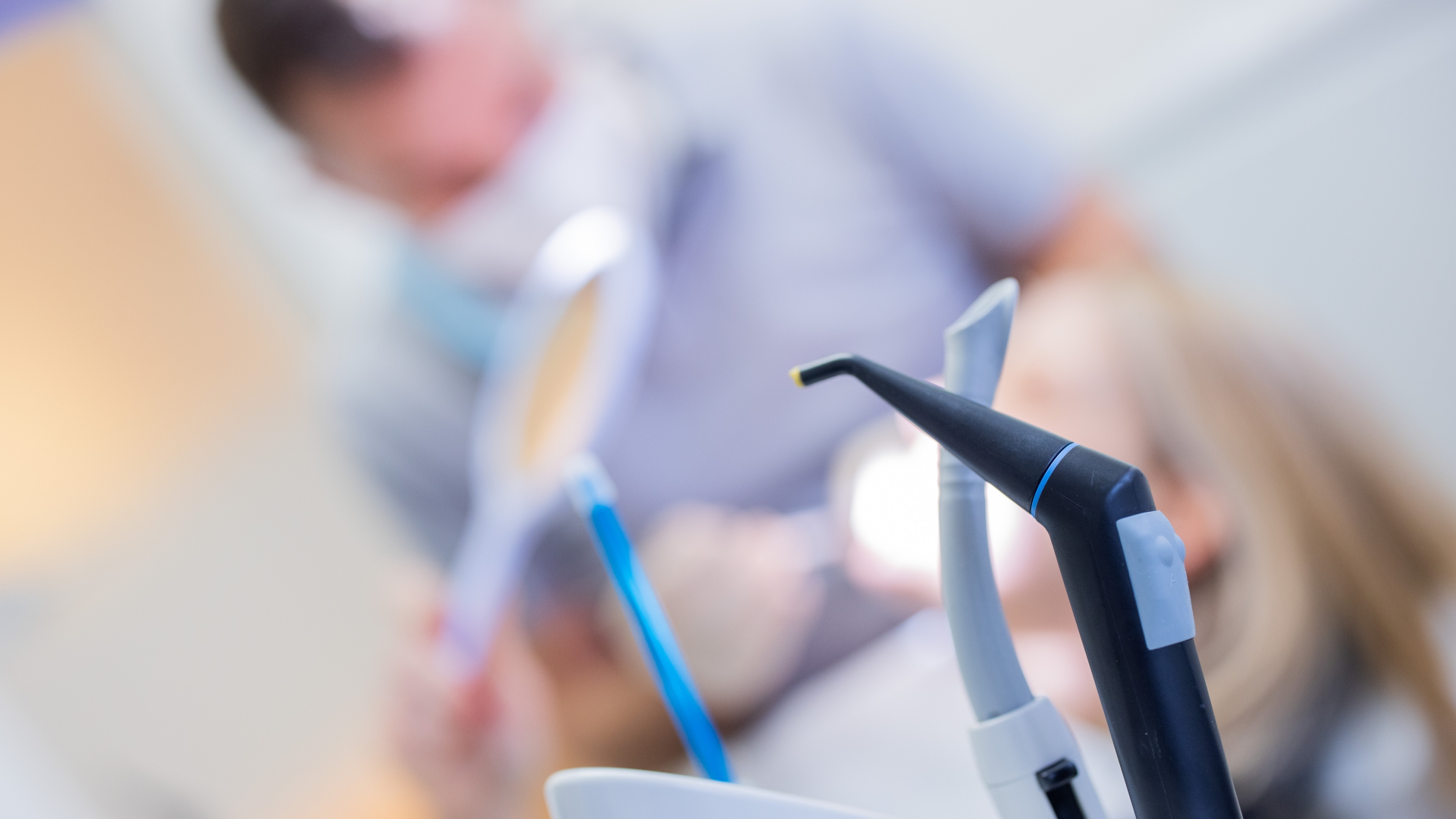 Ein Zahnarzt mit Mund-Nasen-Schutz und Schutzvisier versorgt eine Patientin in einer Praxis | dpa