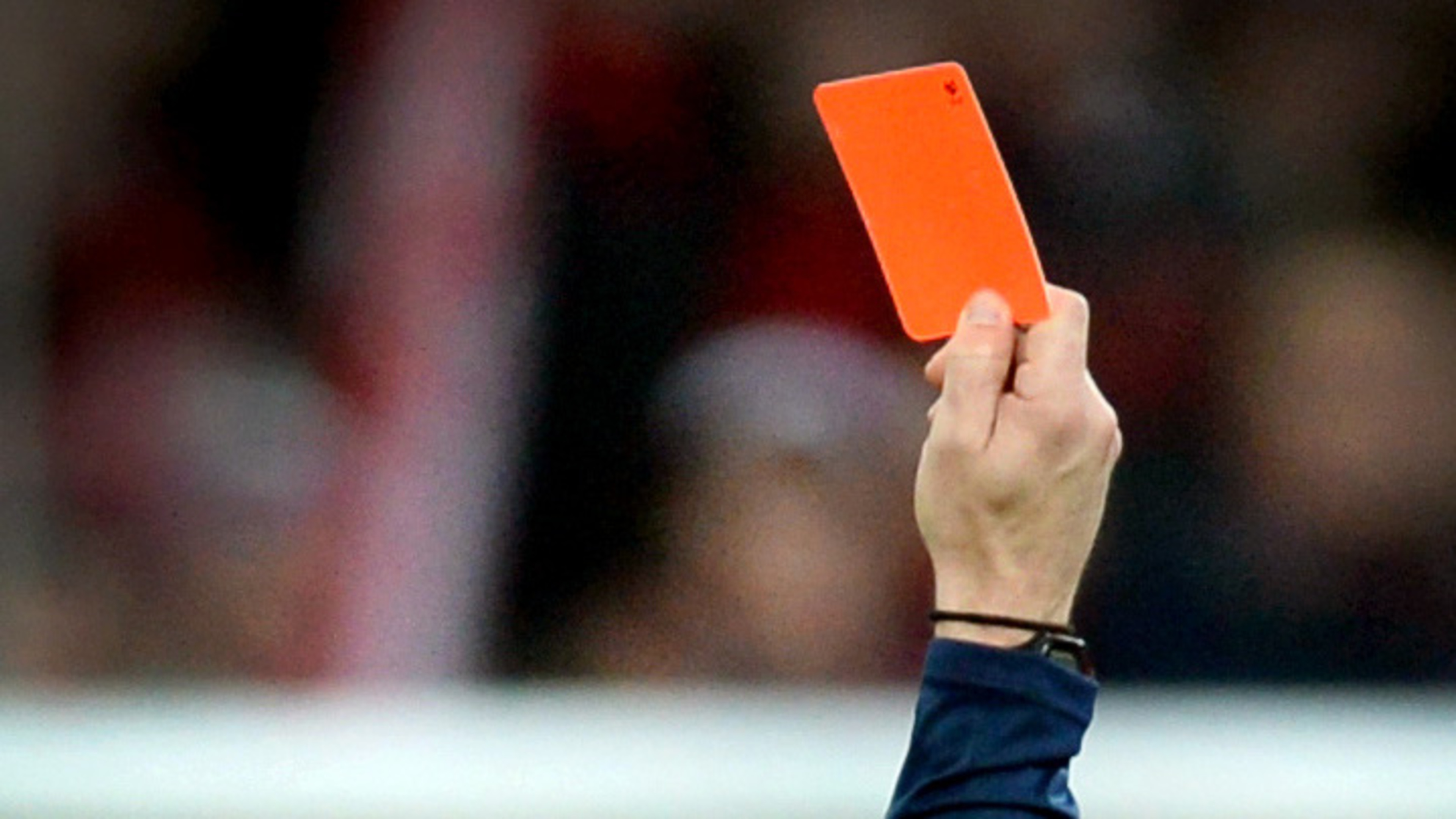 Ein Schiedsrichter zieht eine rote Karte aus seiner Gesäßtasche
