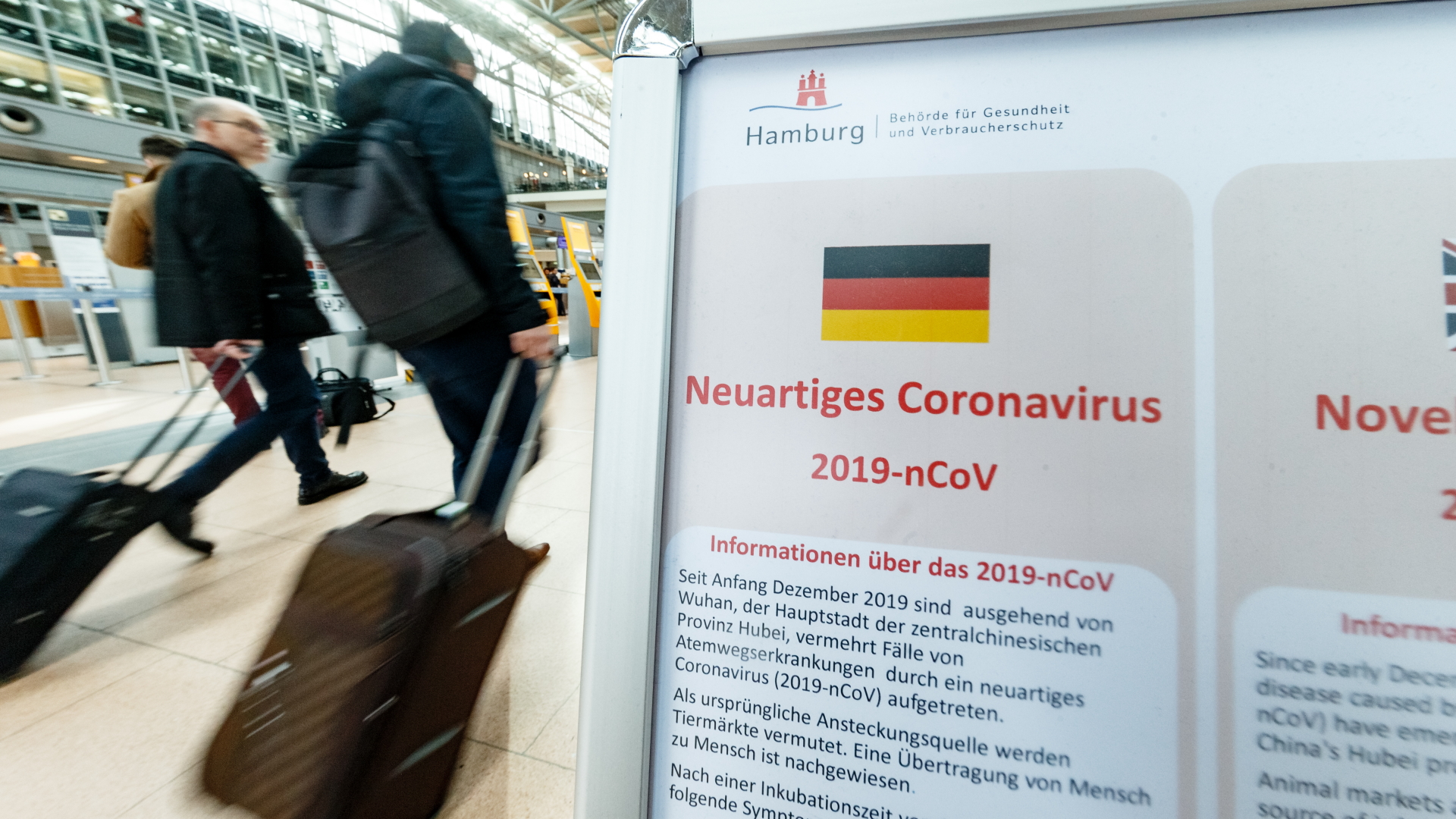 Eine Hinweistafel im Hamburger Flughafen informiert über Infektionsgefahren durch das Coronavirus. | dpa