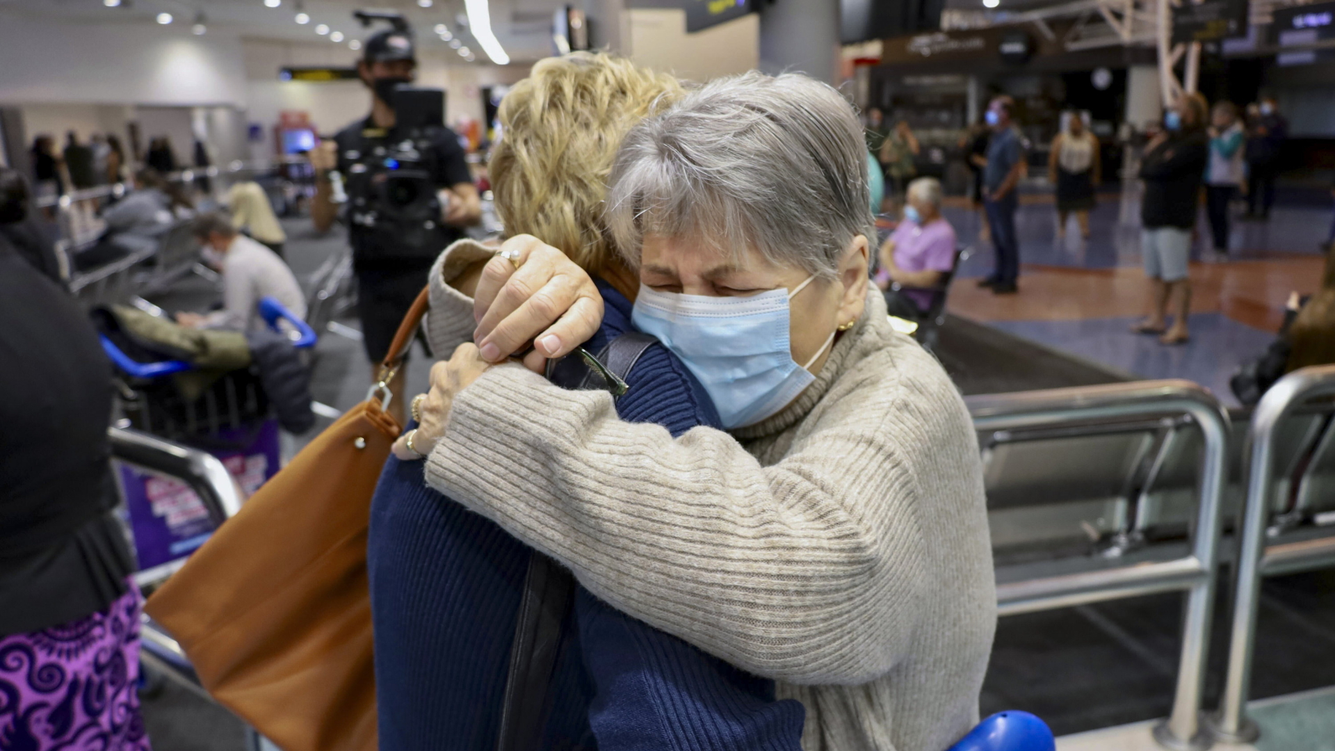 Familienangehörige umarmen sich nach der Ankunft eines Fluges aus Los Angeles auf dem internationalen Flughafen von Auckland  | AP
