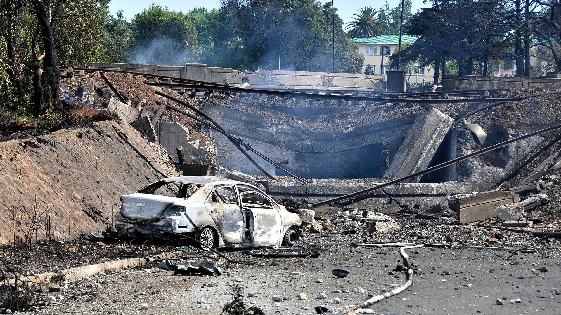 Ein ausgebranntes Fahrzeug markiert die Stelle, an der ein Tankwagen unter einer Brücke im südafrikanischen  Boksburg explodoert ist. | dpa