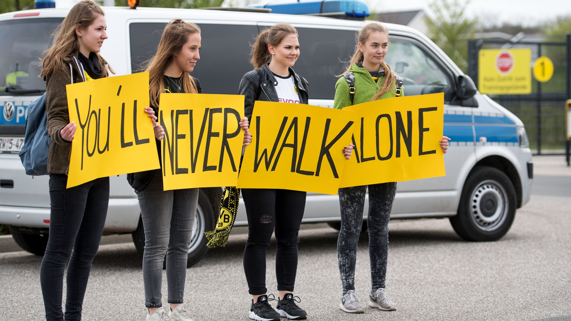 Vier junge Frauen stehen vor dem Trainingsgelände von Borussia Dortmund und halten Schilder mit der Aufschrift "You`ll never walk alone" hoch. | dpa