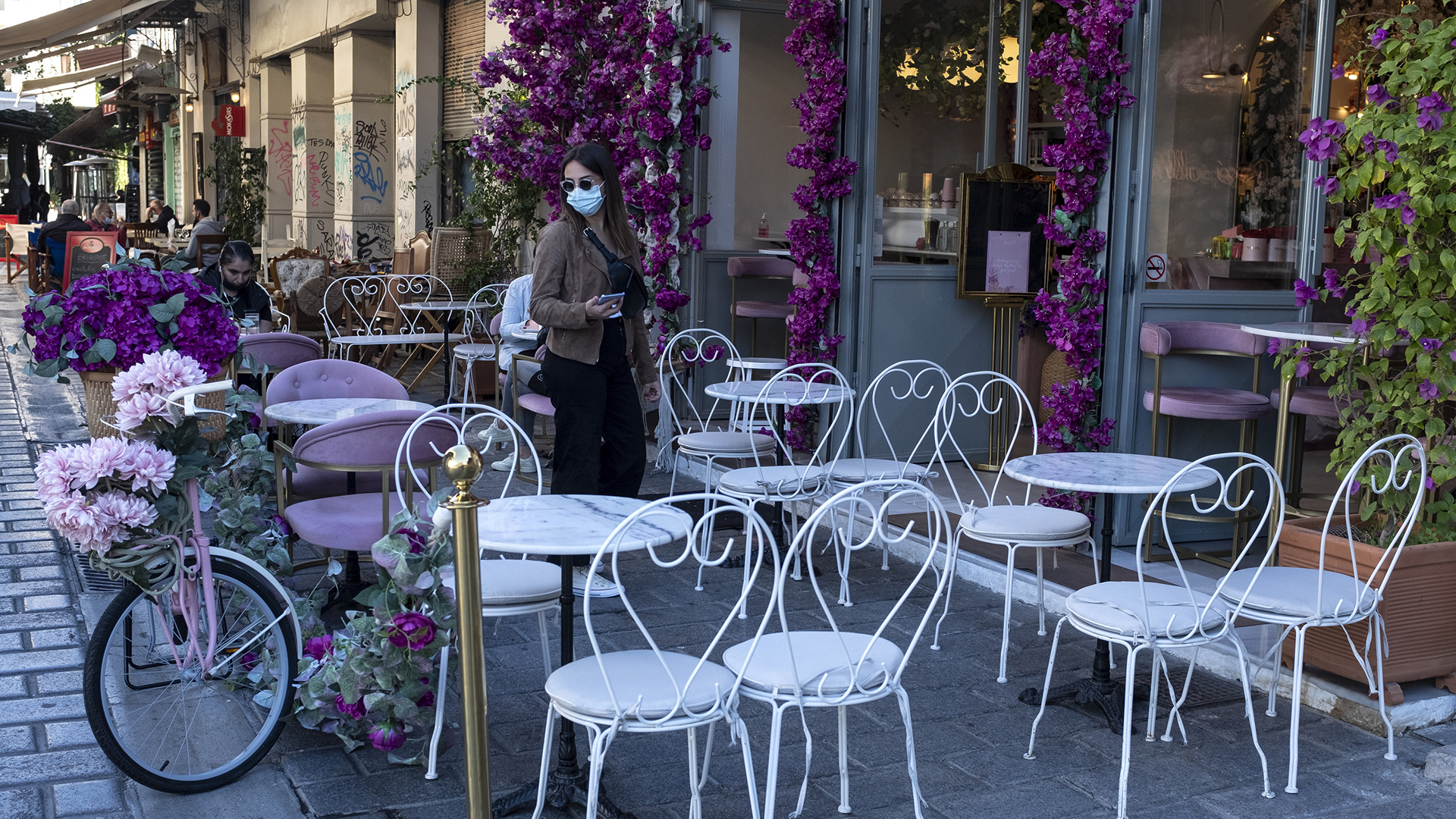 Eine Frau steht vor einem Café in Athen. | AP