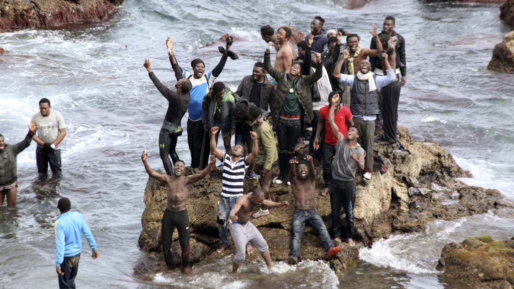 Flüchtlinge zeigen auf einem Felsen an der Mittelmeerküste ihre Freude über die gelungene Flucht in die spanische Exklave Ceuta.