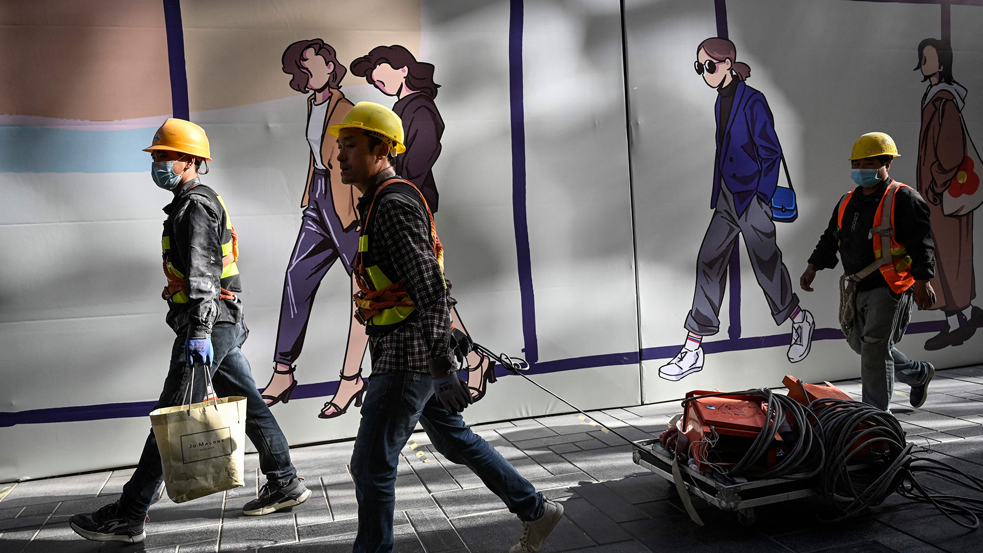 Bauarbeiter gehen an einem Einkaufszentrum vorbei | AFP