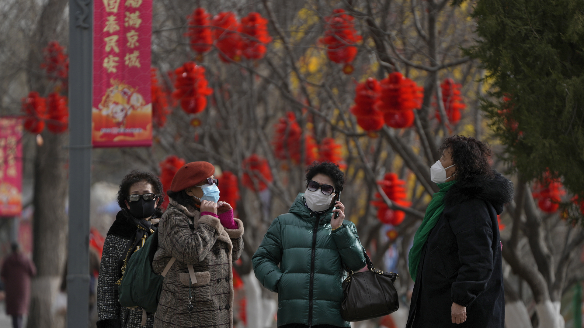 Frauen tragen Mund-Nasen-Schutz während sie einen Park in Peking besuchen, der mit Dekorationen zum chinesische Neujahrsfest geschmückt ist. | dpa