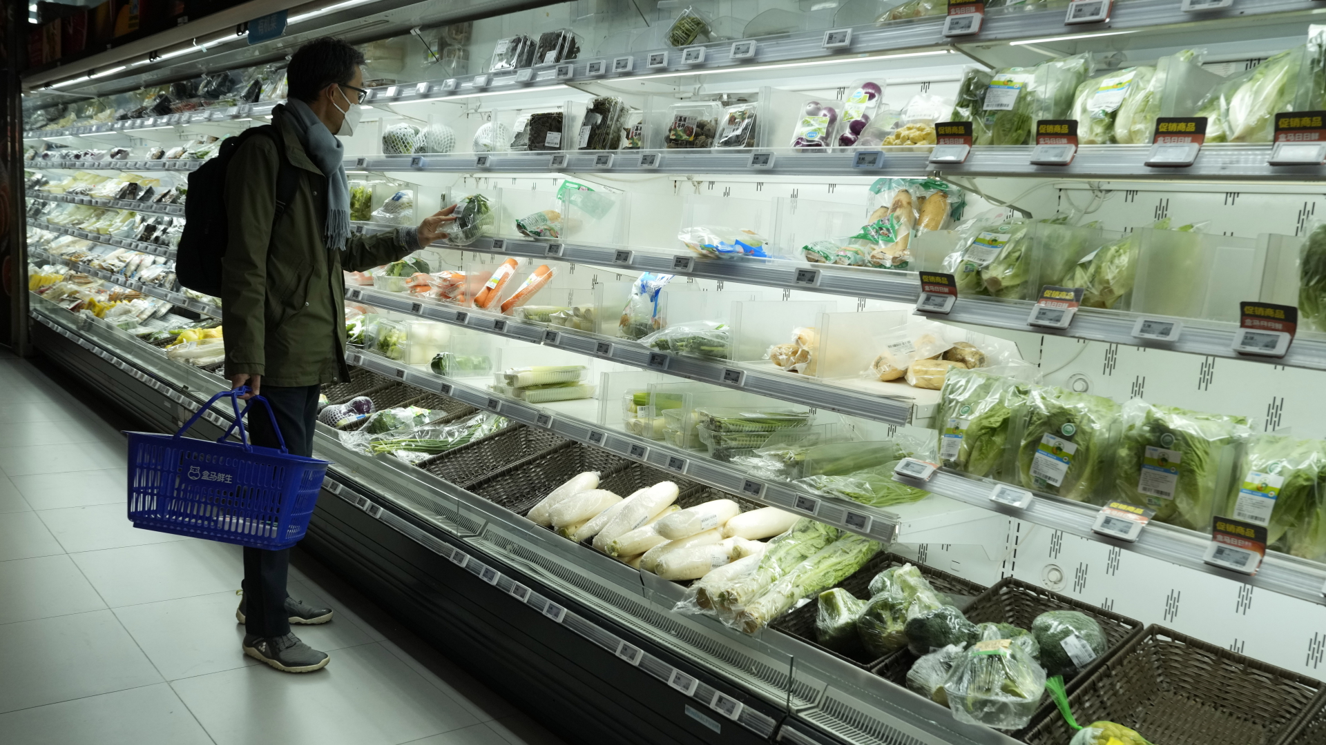 Ein Mann mit FFP2-Maske steht in Peking vor einem Frischeregal in einem Supermarkt. | dpa