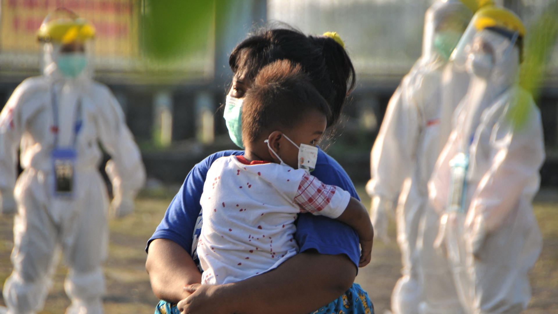 Eine Frau trägt ihr Kind auf eine Corona-Isolierstation in Indonesien | AFP