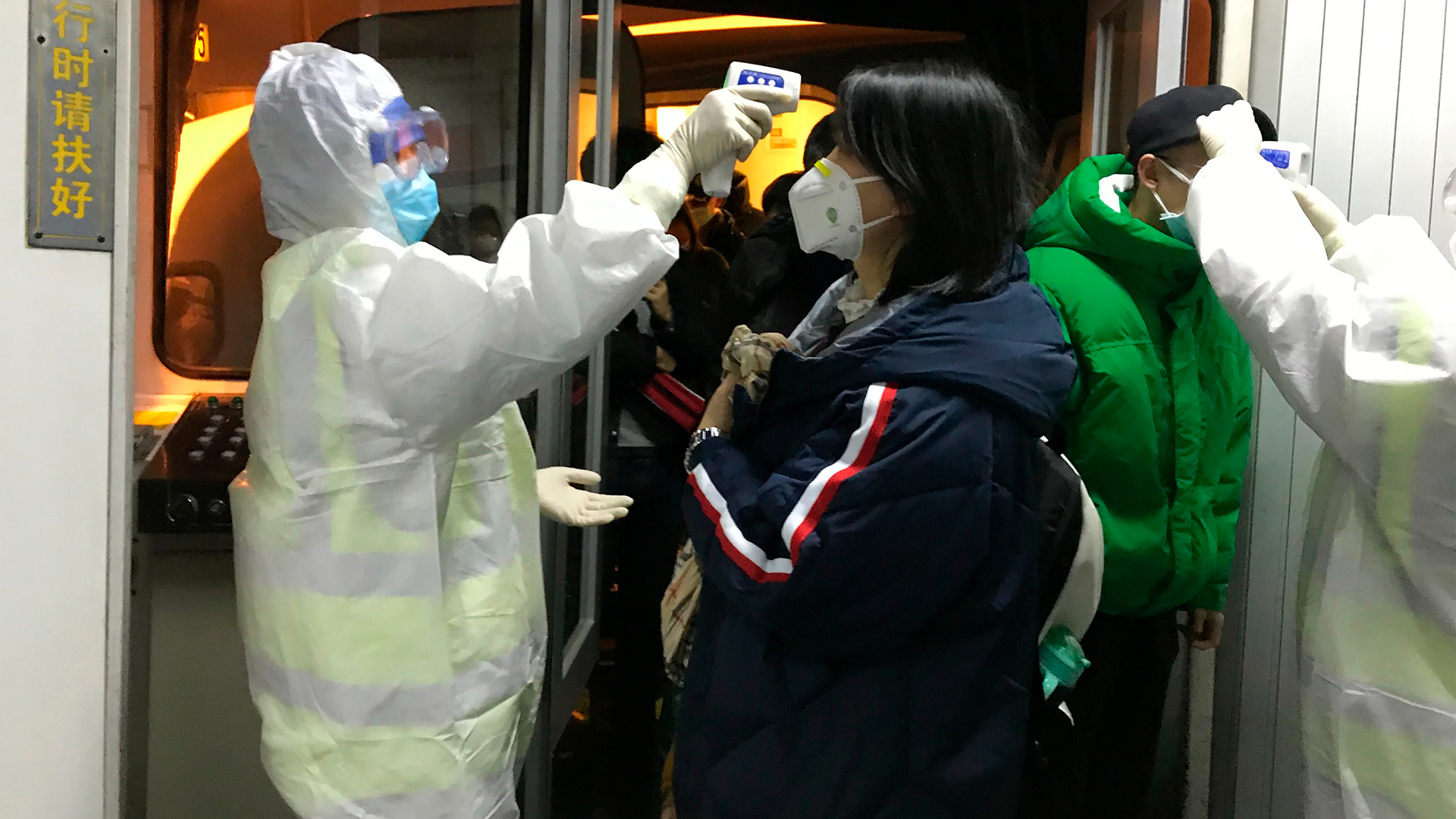 Gesundheitsbeamte in Chemikalienschutzanzügen kontrollieren am Flughafen die Körpertemperatur von Passagieren, die aus der Stadt Wuhan angereist sind. | dpa