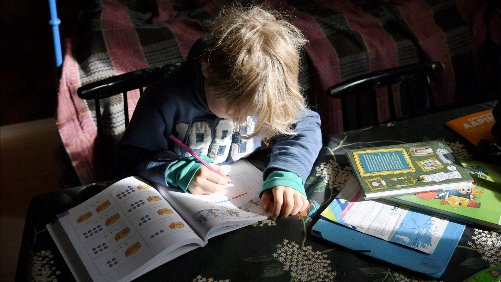Ein Junge sitzt in Helsinki zu Hause an einem Tisch und schreibt in einem Schulheft. | dpa