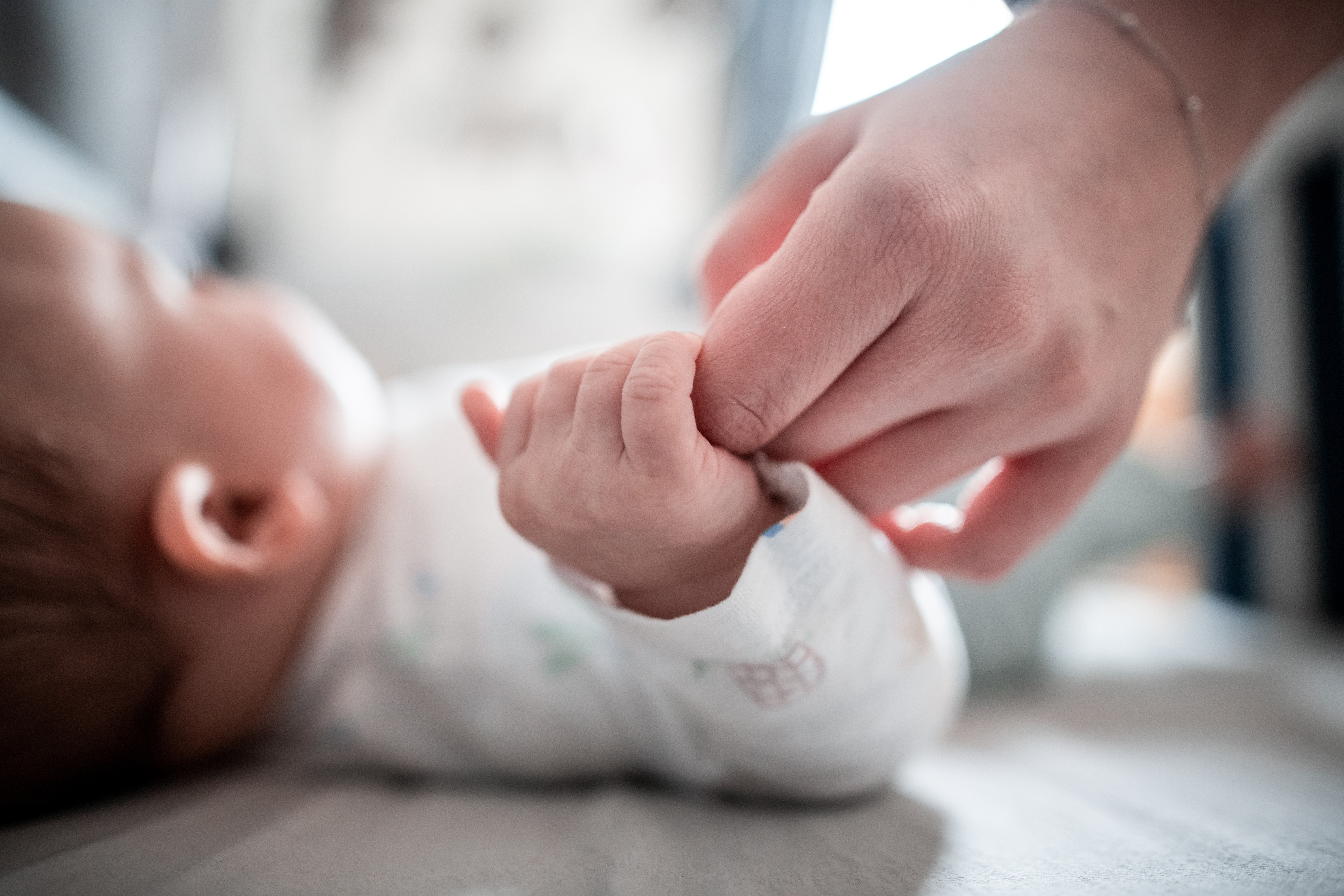Ein Baby klammert sich an den Finger seiner Mutter.  | dpa