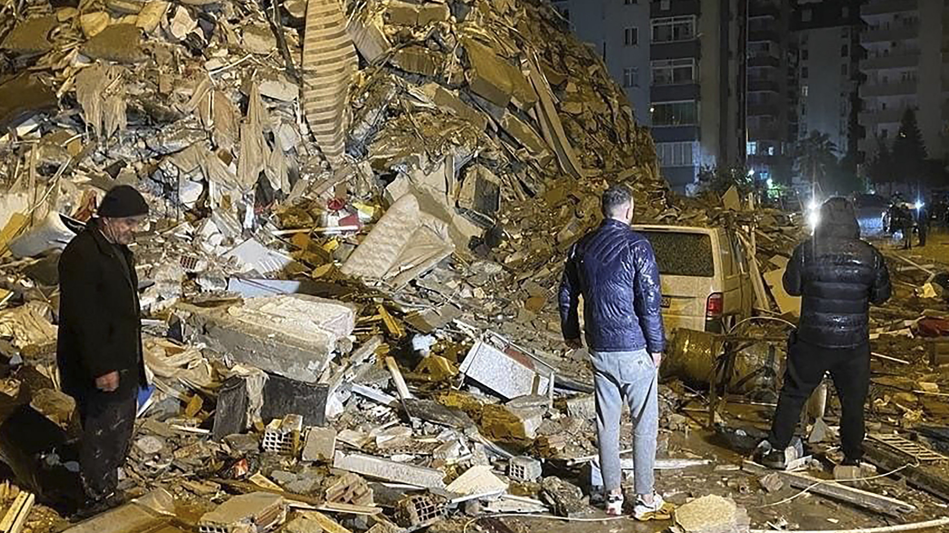Menschen stehen vor einem zerstörten Gebäude in Diyarbakair in Südostanatolien in der Türkei. | AP