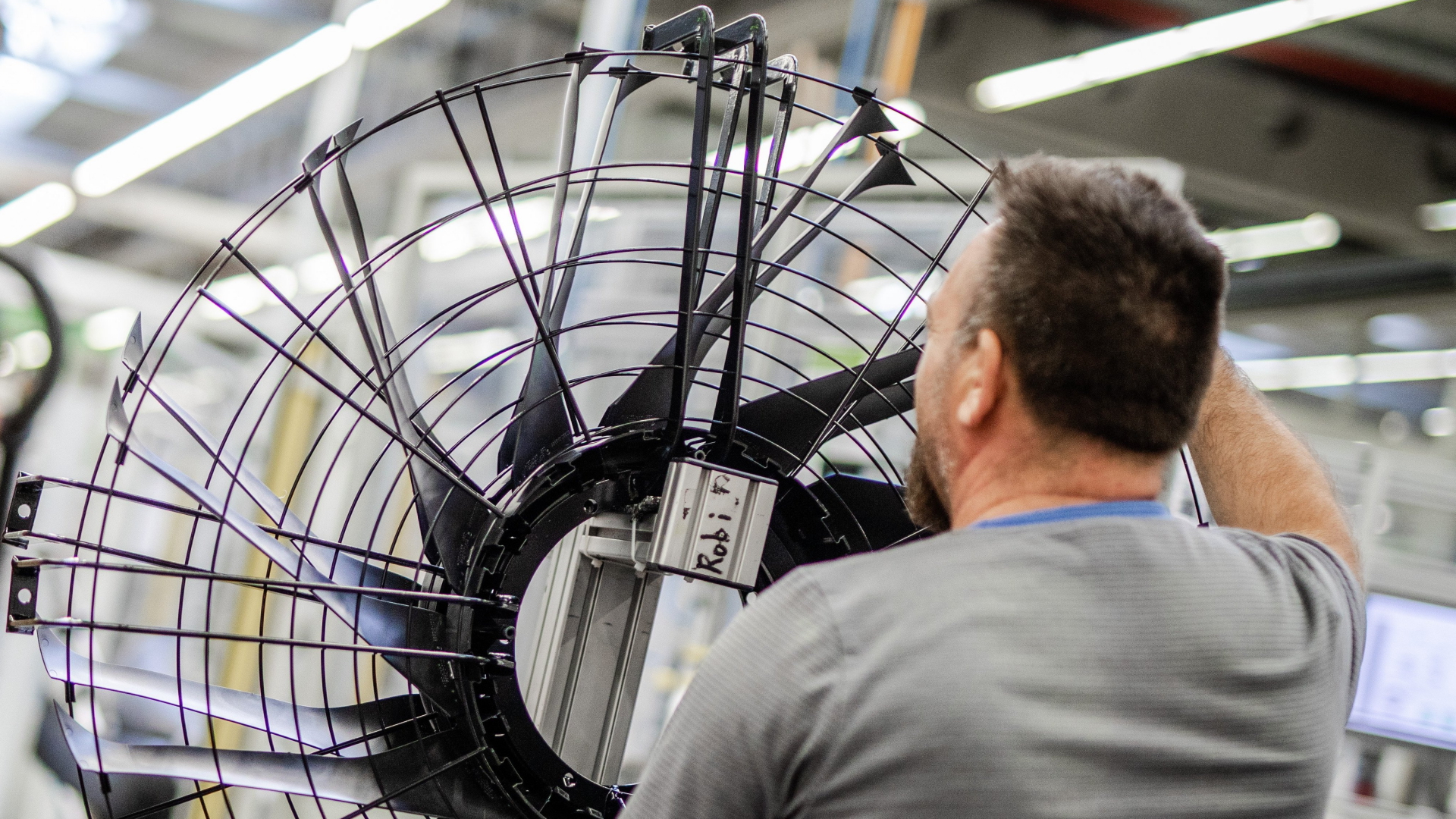 Ein Mitarbeiter eines Elektromotoren- und Ventilatorenherstellers arbeitet in der Produktion an einem Ventilator.  | dpa