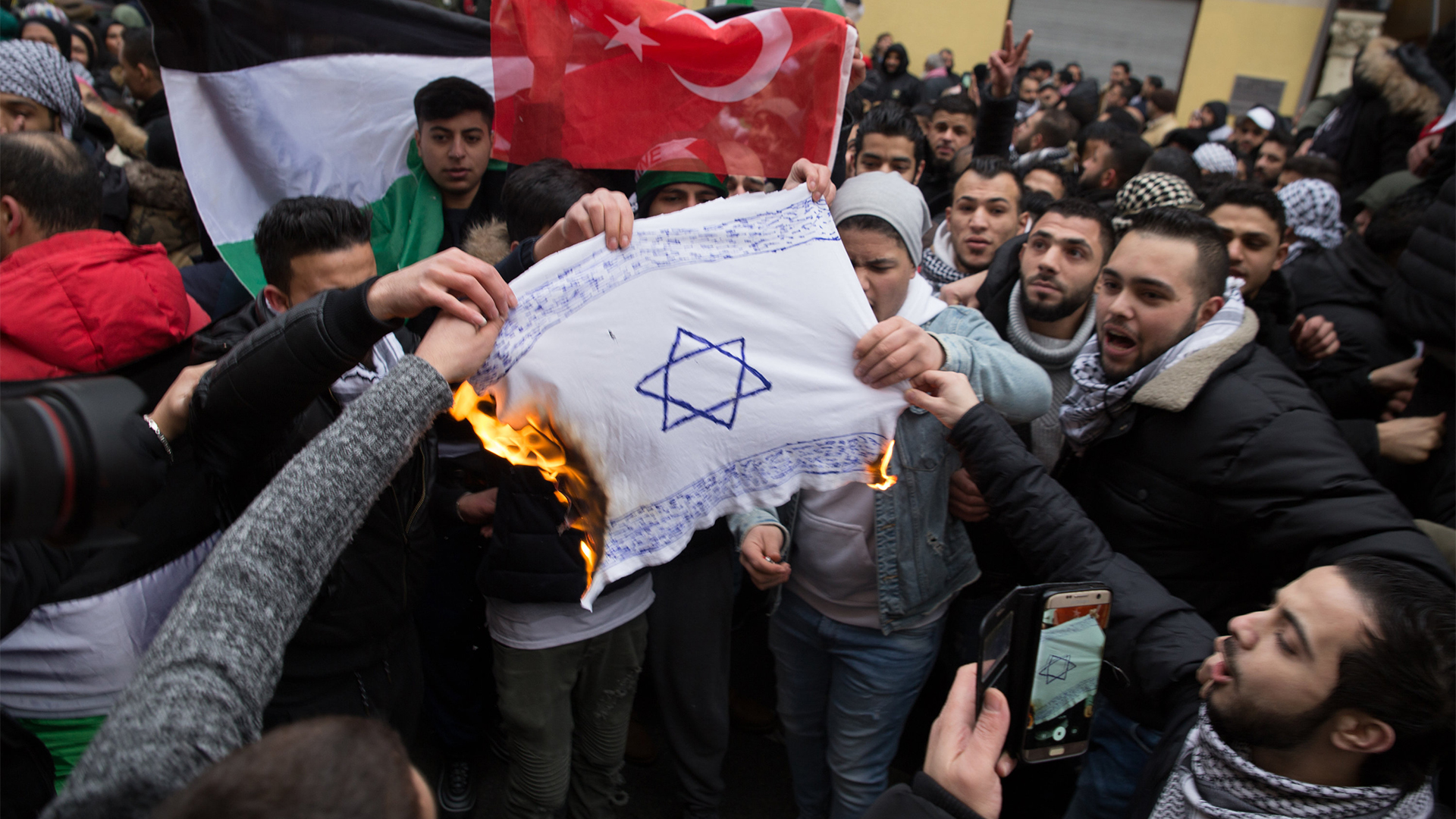 Teilnehmer einer Demonstration verbrennen am 10.12.2017 eine Fahne mit einem Davidstern in Berlin im Stadtteil Neukölln. (Quelle: Jüdisches Forum für Demokratie und gegen Antisemitismus e.V./dpa) | dpa / JFDA