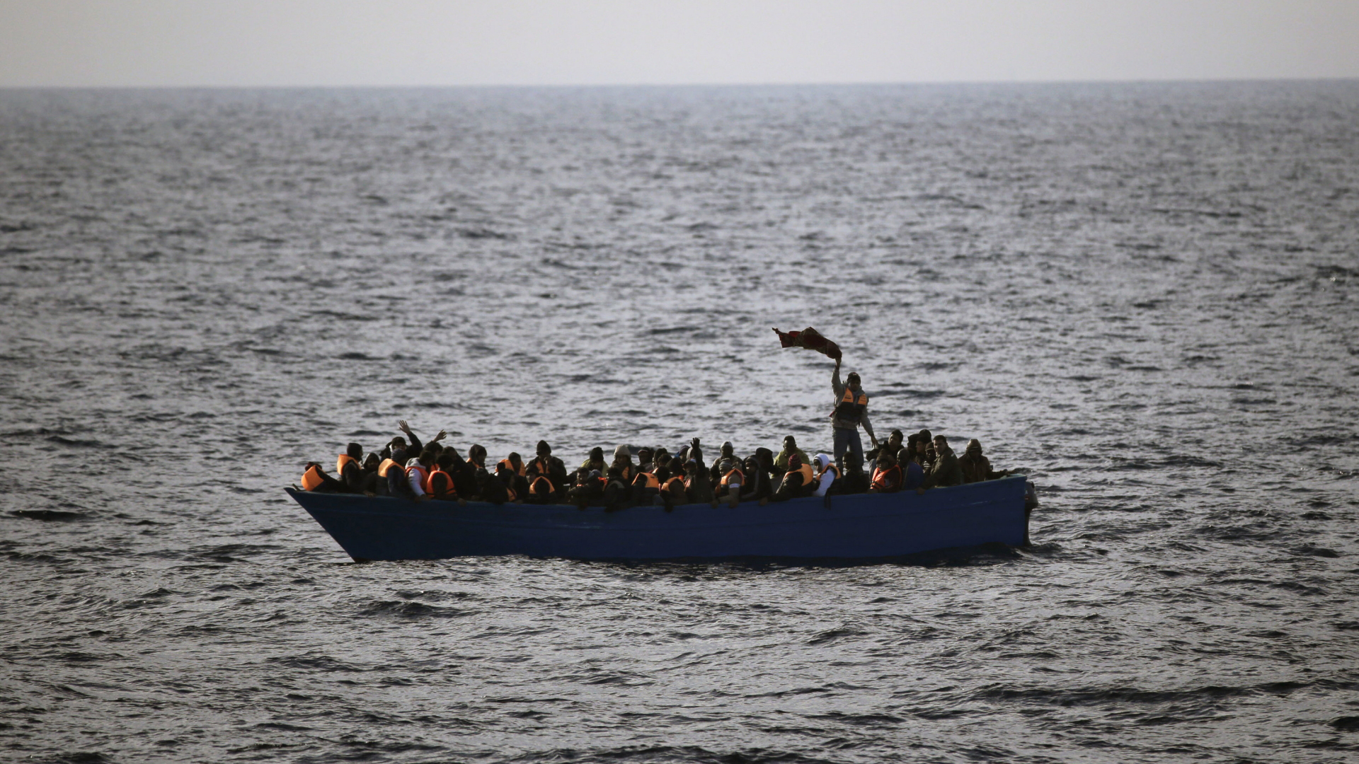Flüchtlinge rufen auf einem Boot im Mittelmeer um Hilfe | dpa