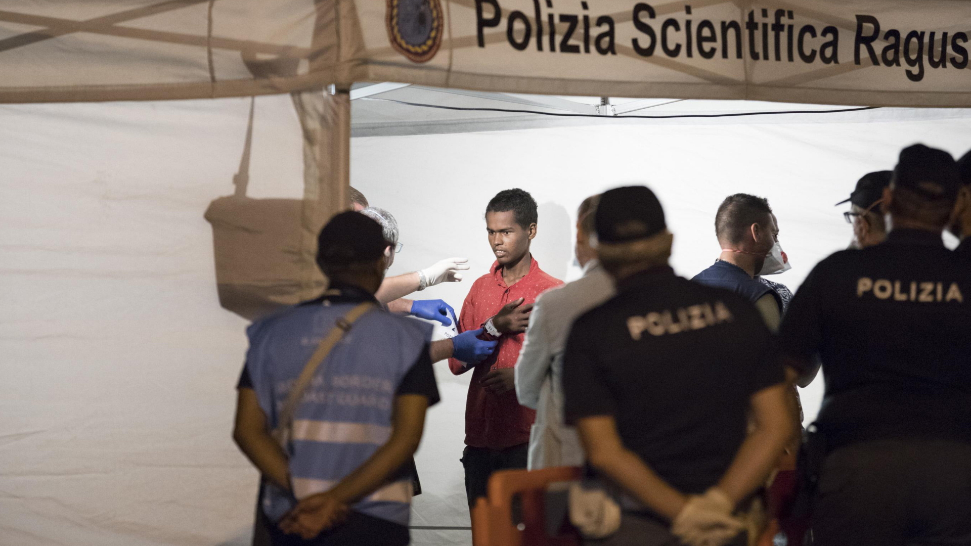 Polizisten kontrollieren einen Migranten in Italien. | AP