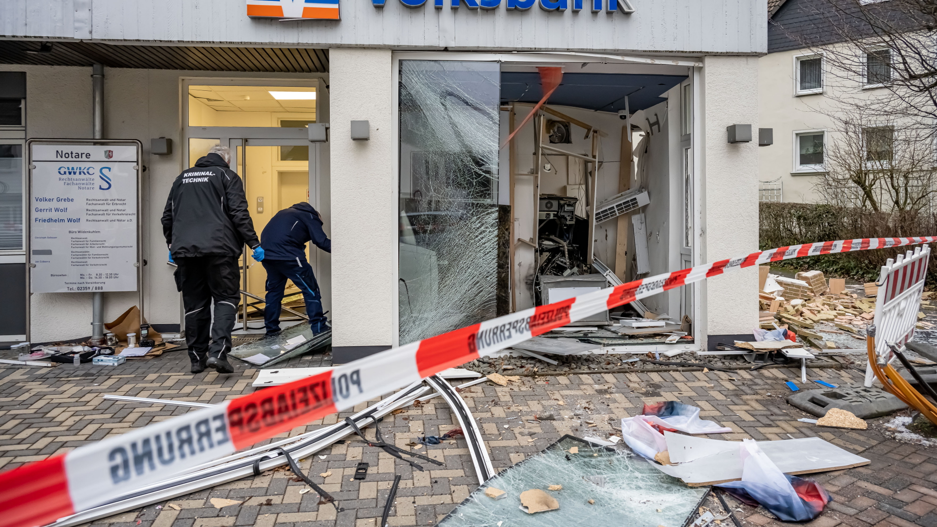 Mitarbeiter der Kriminaltechnik untersuchen eine schwer beschädigte Bankfiliale | dpa
