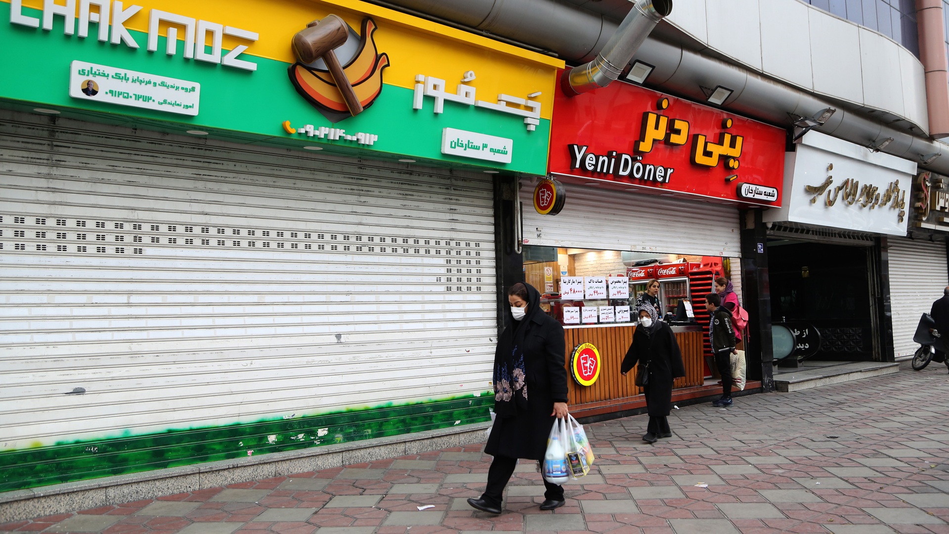 Passantinnen gehen an geschlossenen Geschäften in Teheran vorüber. | picture alliance / AA