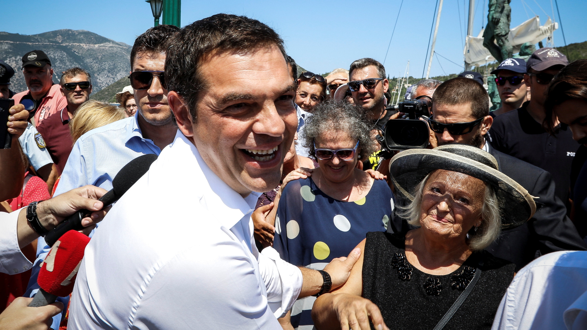 Griechenlands Regierungschef Tsipras lächelt in die Kamera, während er Einwohnern der Insel Ithaka die Hände schüttelt. | REUTERS