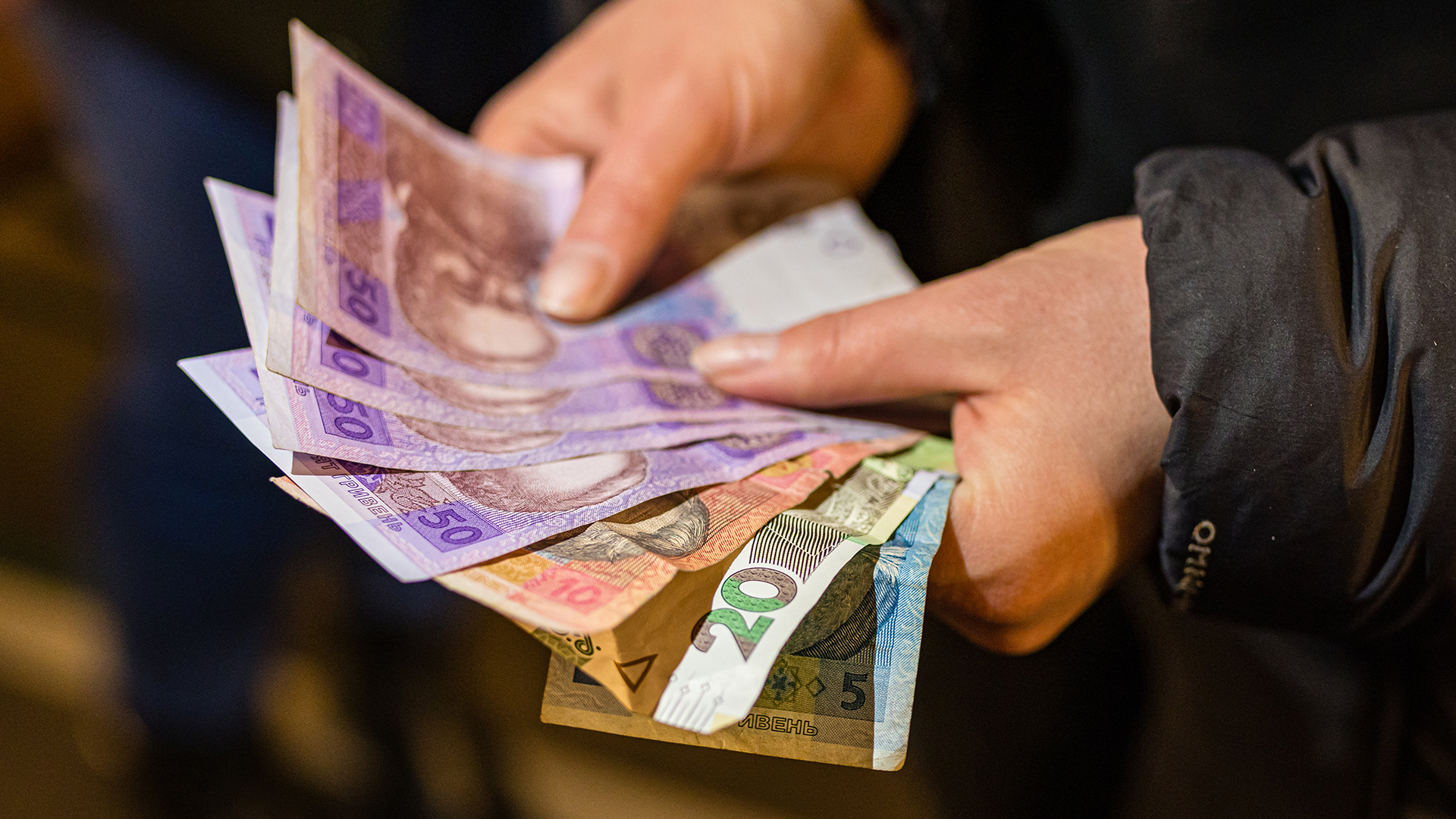 Hände halten ukrainische Geldscheine. | dpa